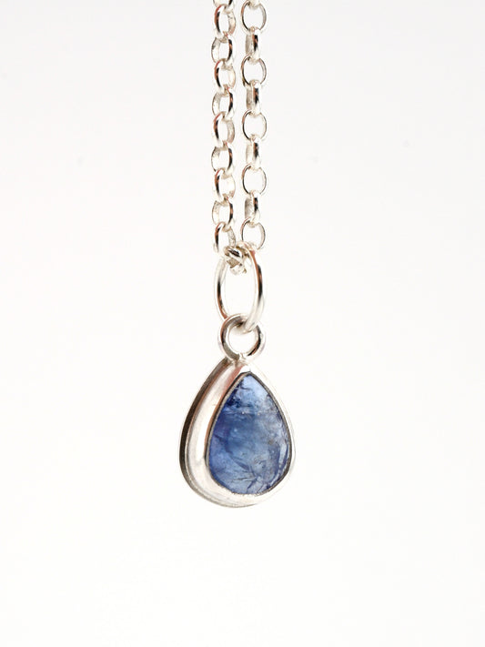 Teardrop-shaped blue stone pendant on a silver chain against a white background