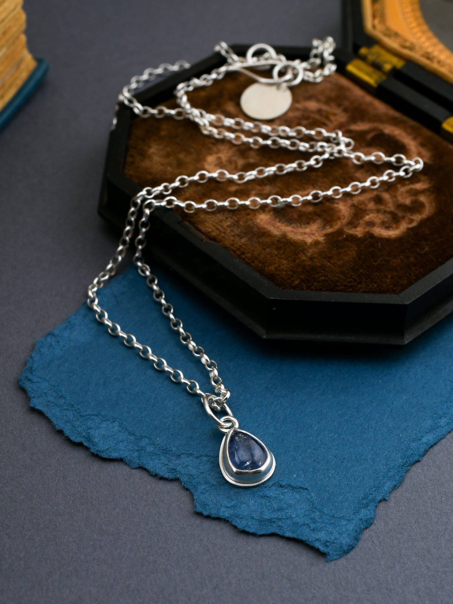 Silver necklace with a teardrop pendant on a textured surface