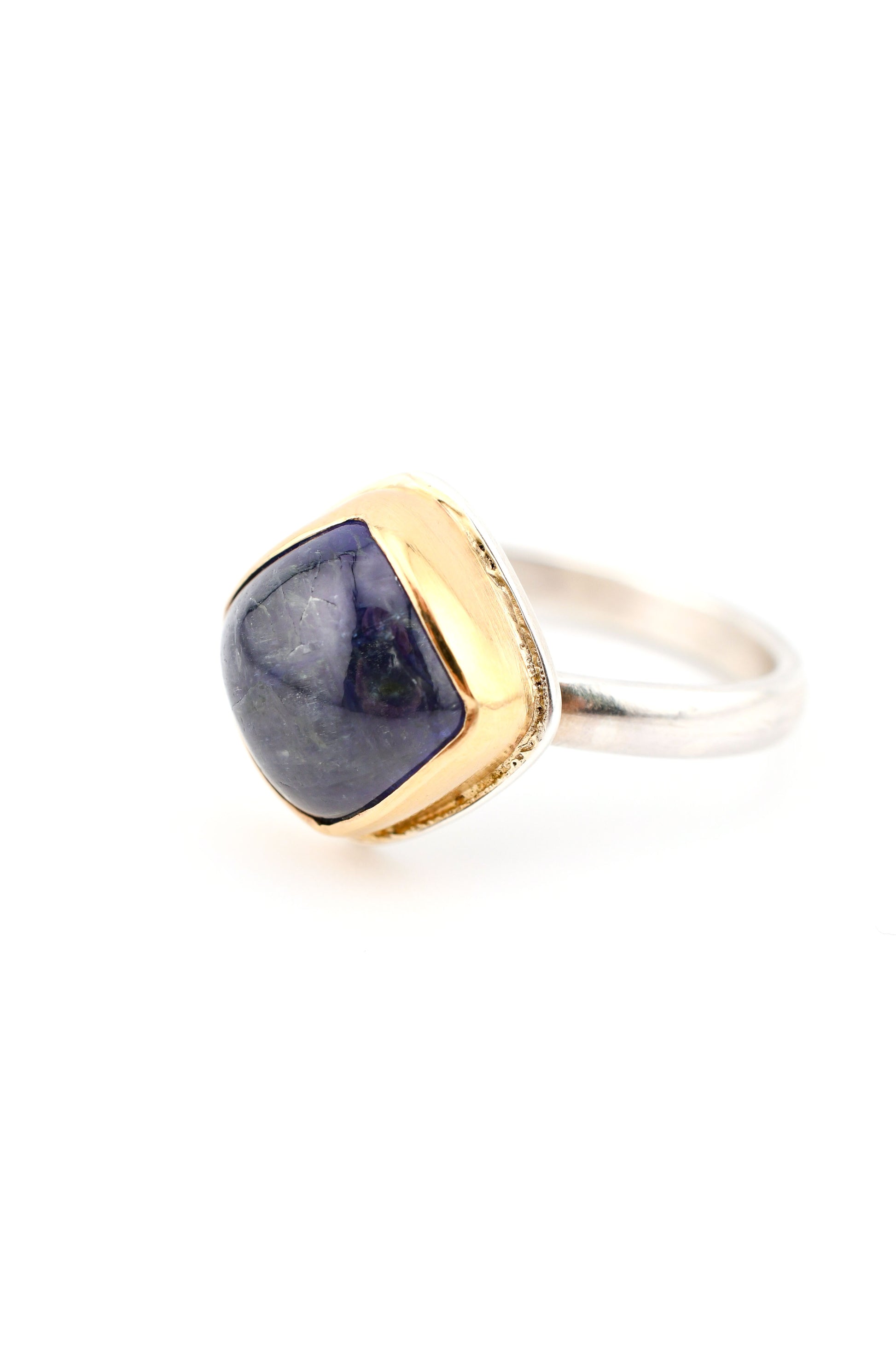 Ring with gold and silver band and blue stone on a white background