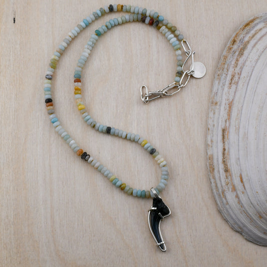 Necklace with beaded chain and shark tooth pendant on a wooden surface