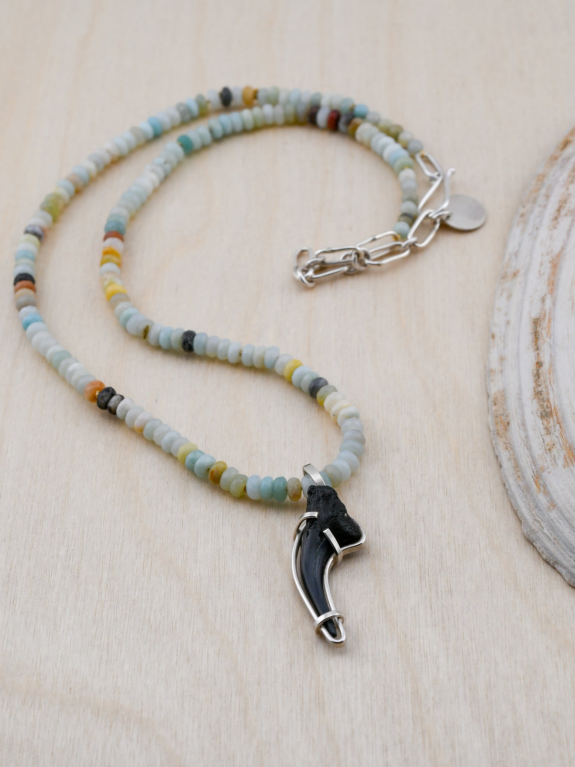 Necklace with beaded chain and unique pendant on a wooden surface