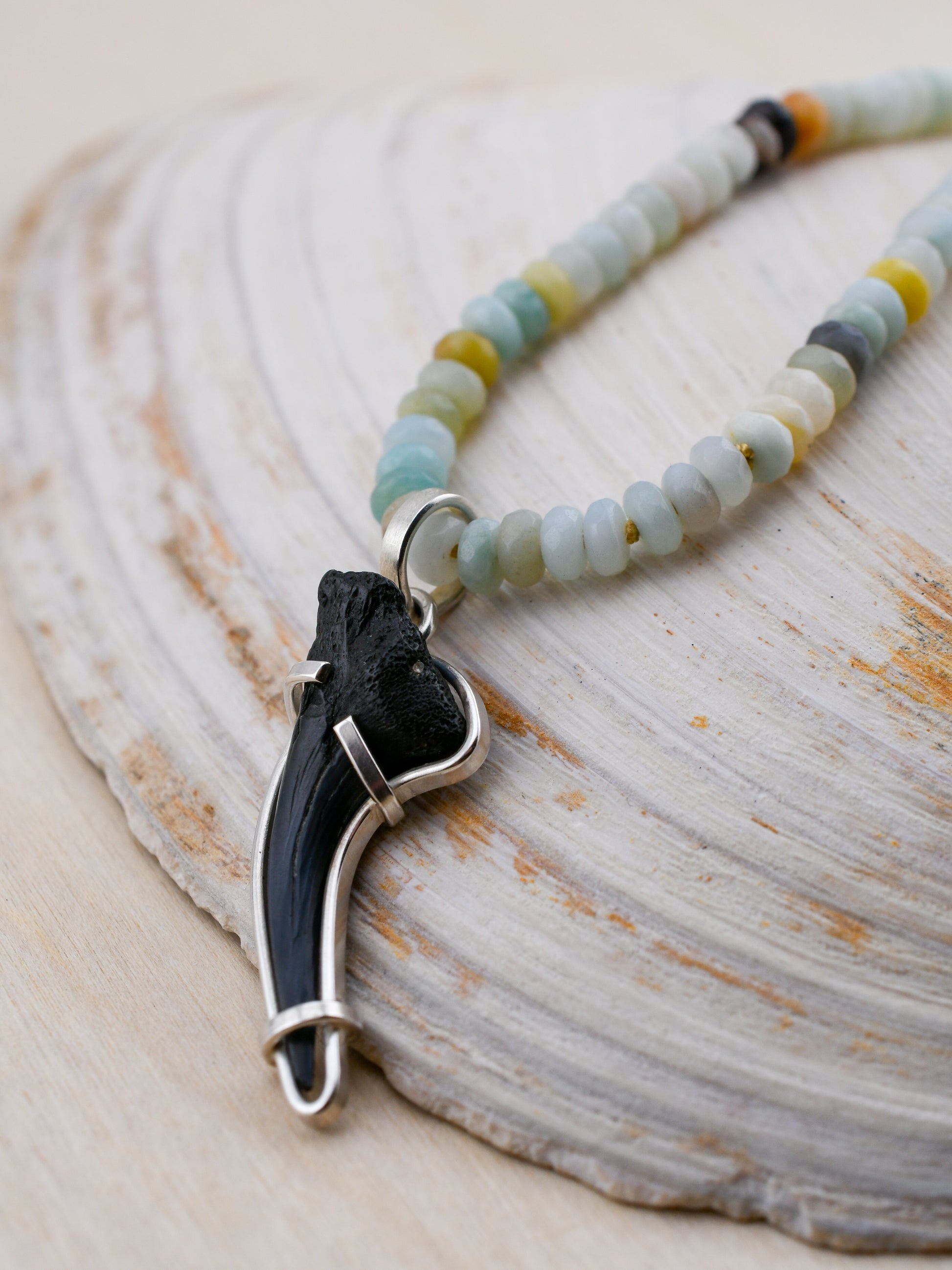 Necklace with a black and silver pendant on a textured surface