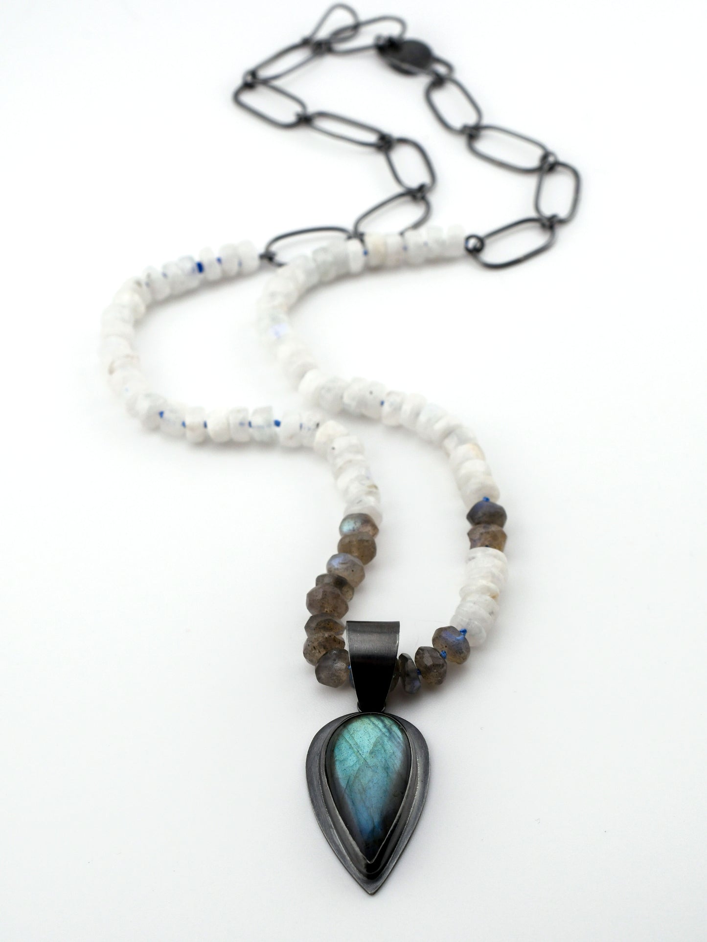 Necklace with a pendant featuring a blue stone on a white background