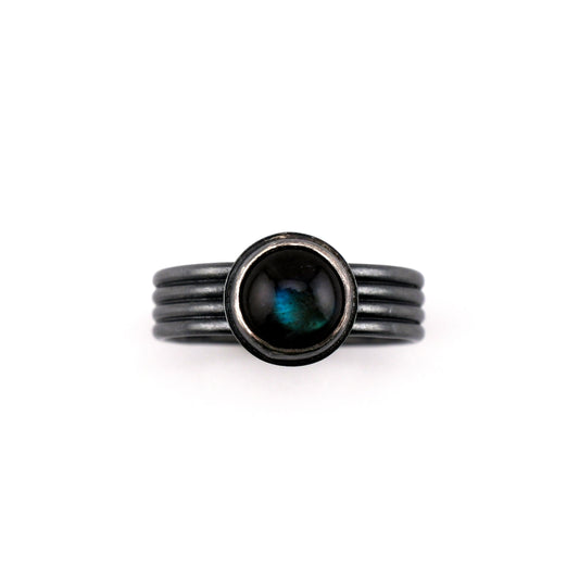 Black ring with a central gemstone on a white background