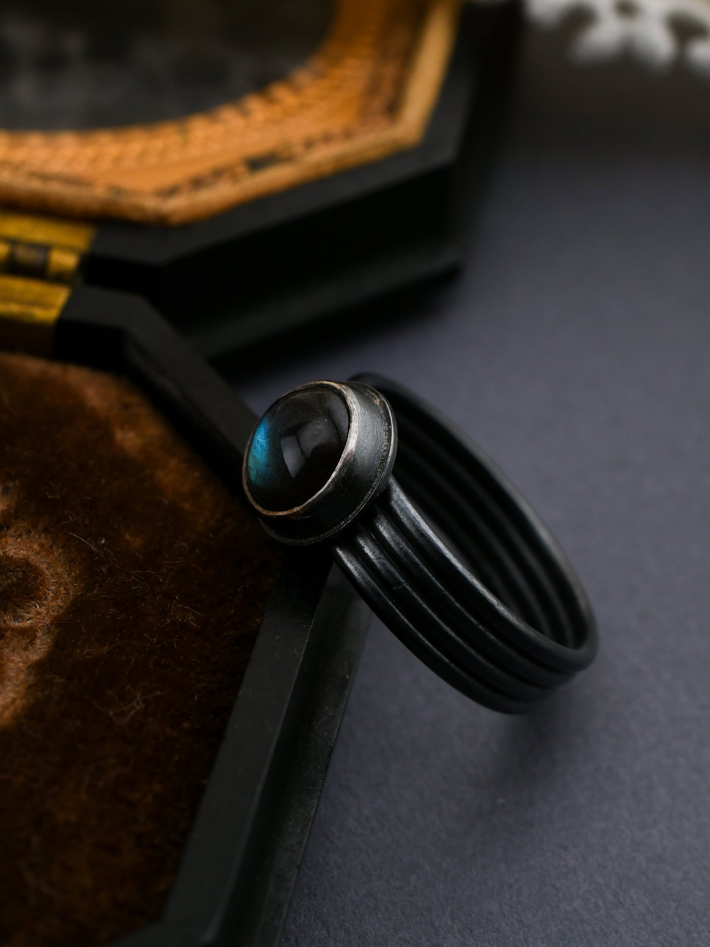 Black ring with a central gemstone on a textured surface