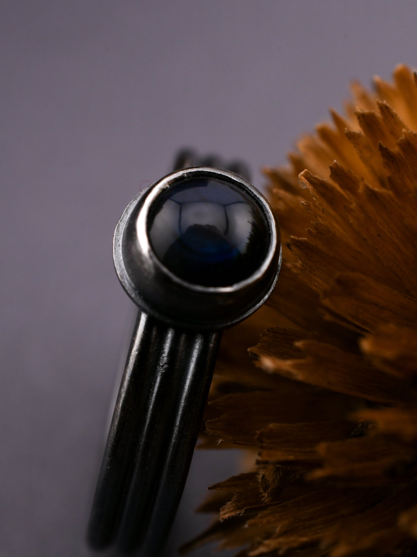 Black metal ring with a central black gemstone on a dark background
