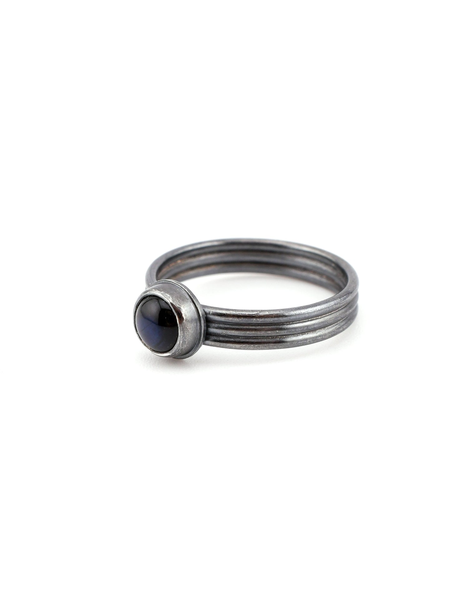 Stack of silver rings with a central dark blue gemstone on a white background