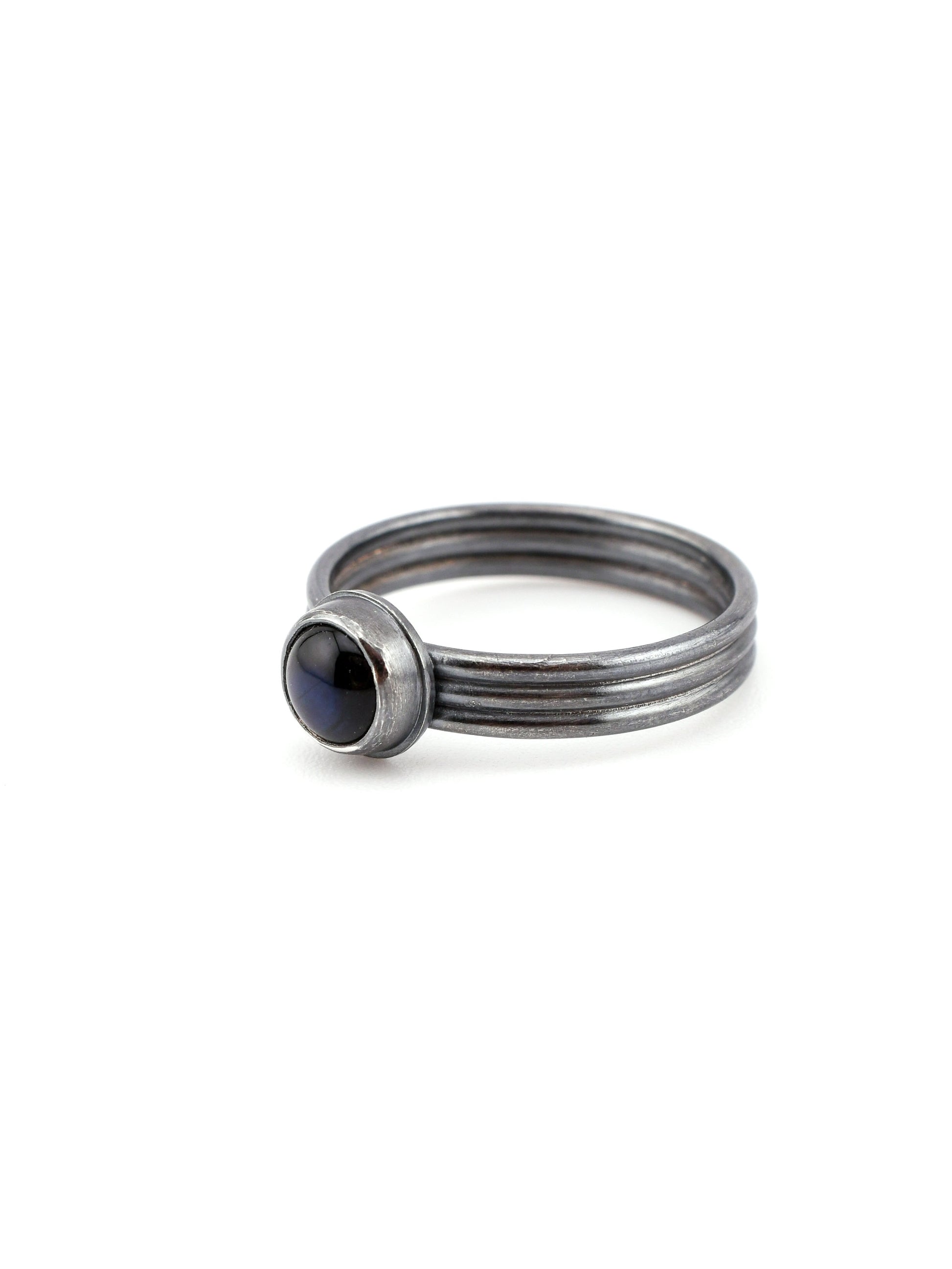 Stack of silver rings with a central dark blue gemstone on a white background