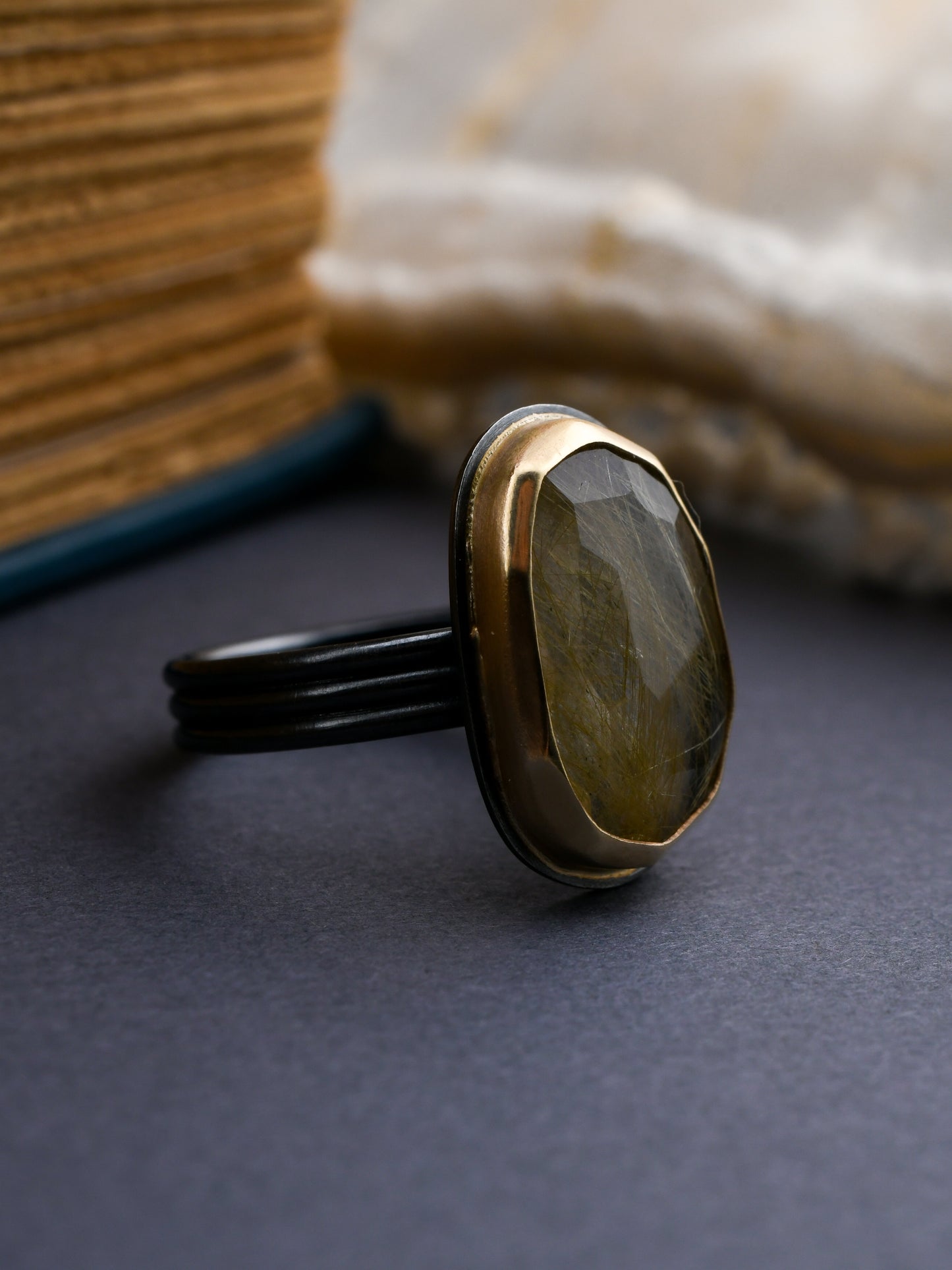 Gold and black silver ring with a stone on a dark surface with a dark gray background