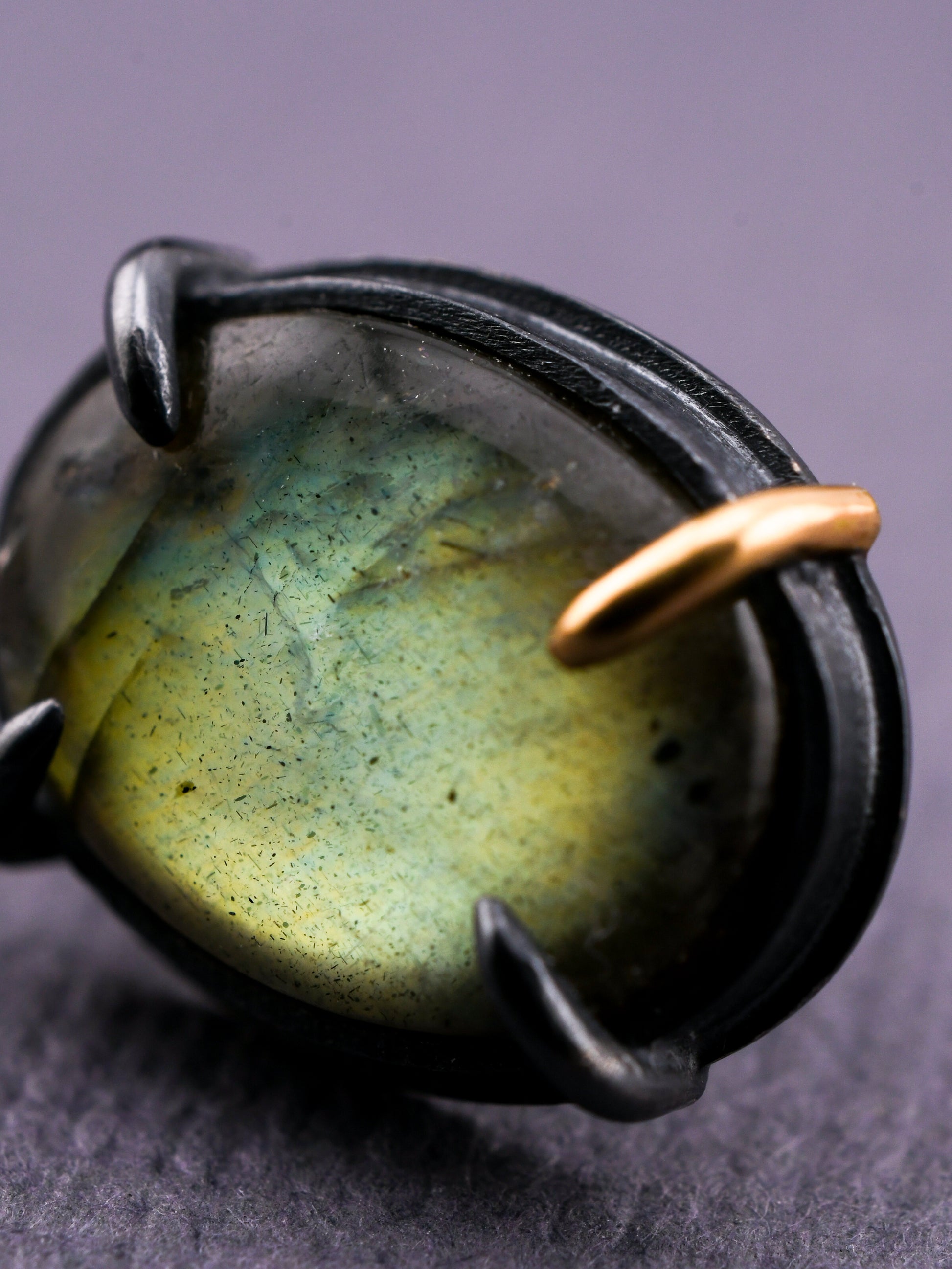 Close-up of a ring with a green stone and gold accent on a dark background