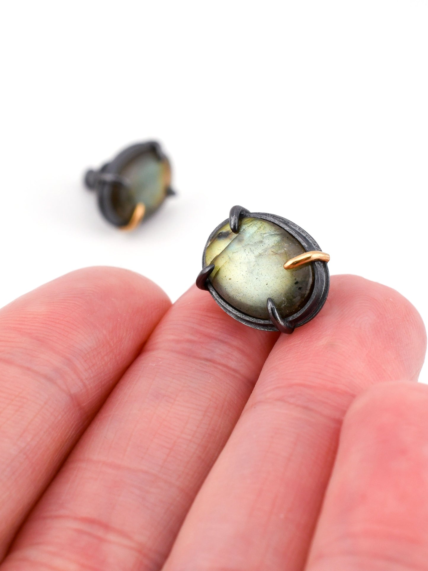 Close-up of a pair of earrings held between fingers on a white background