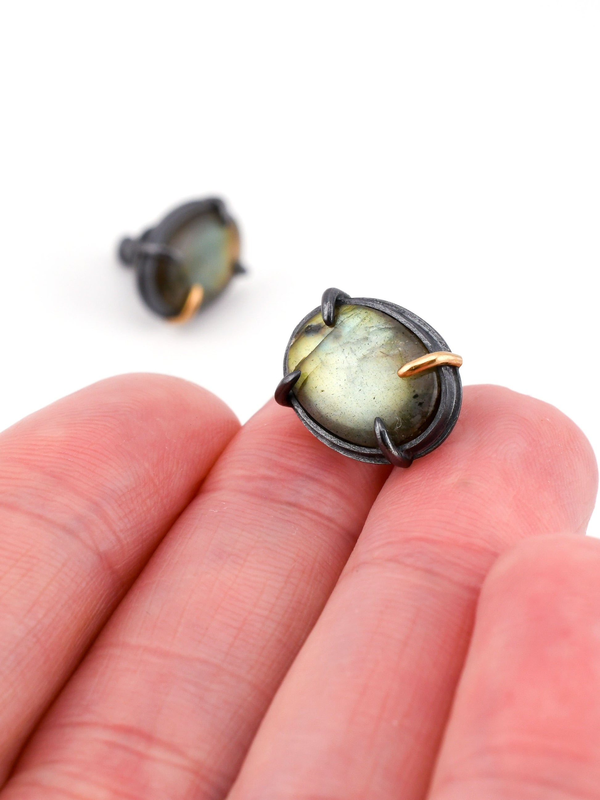 Close-up of a pair of earrings held between fingers on a white background