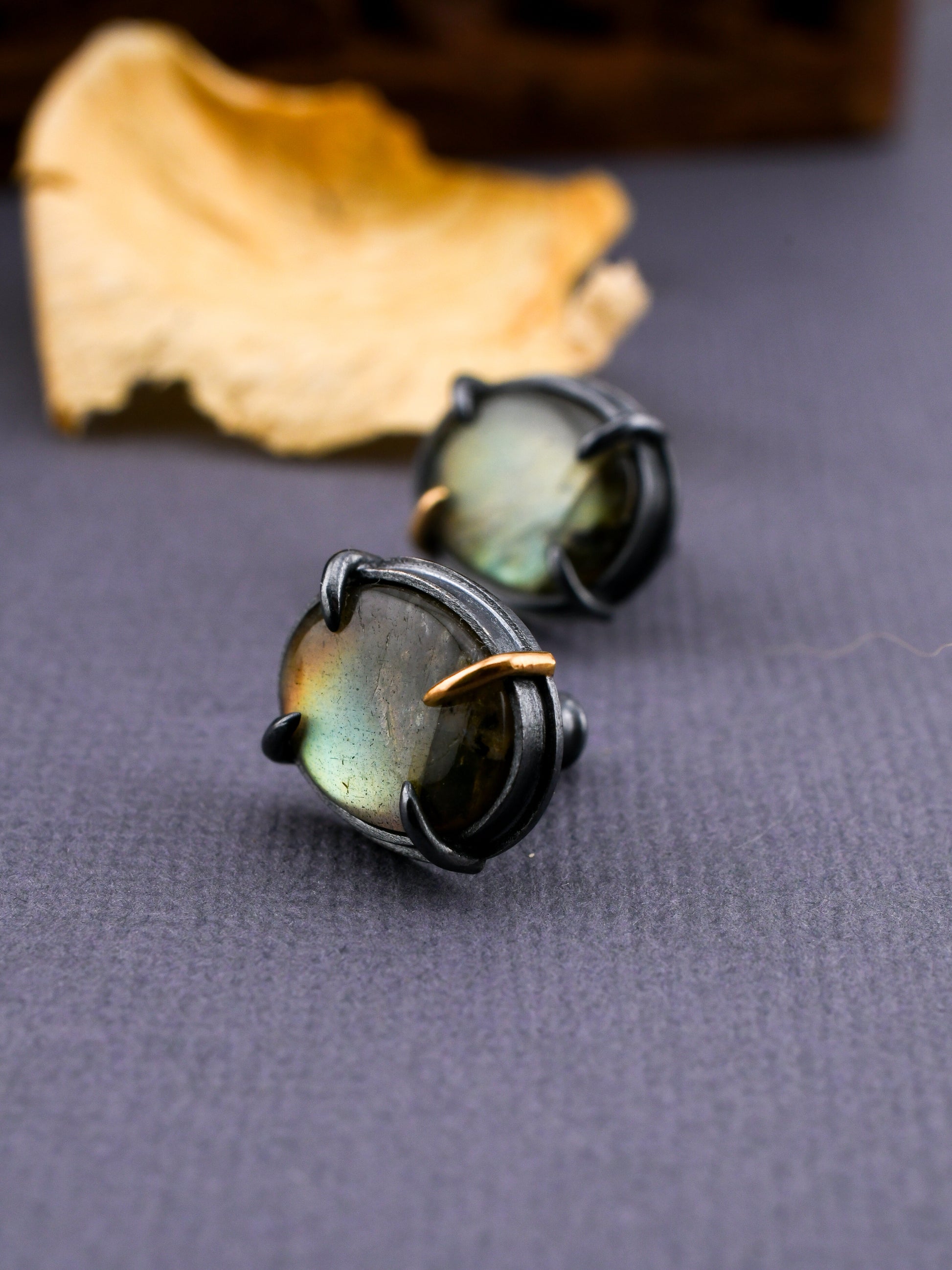 Pair of earrings with green gemstones on a gray surface