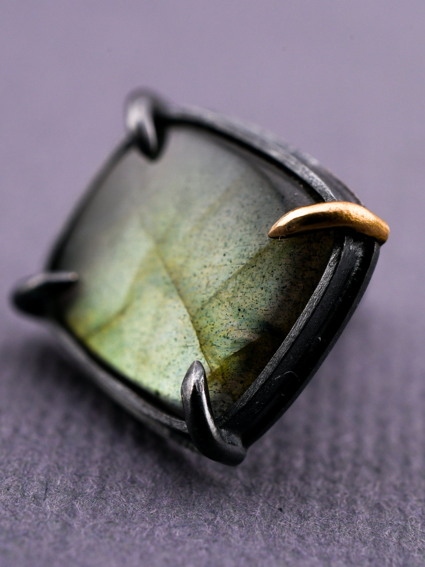 Ring with a green stone and gold accent on a gray background