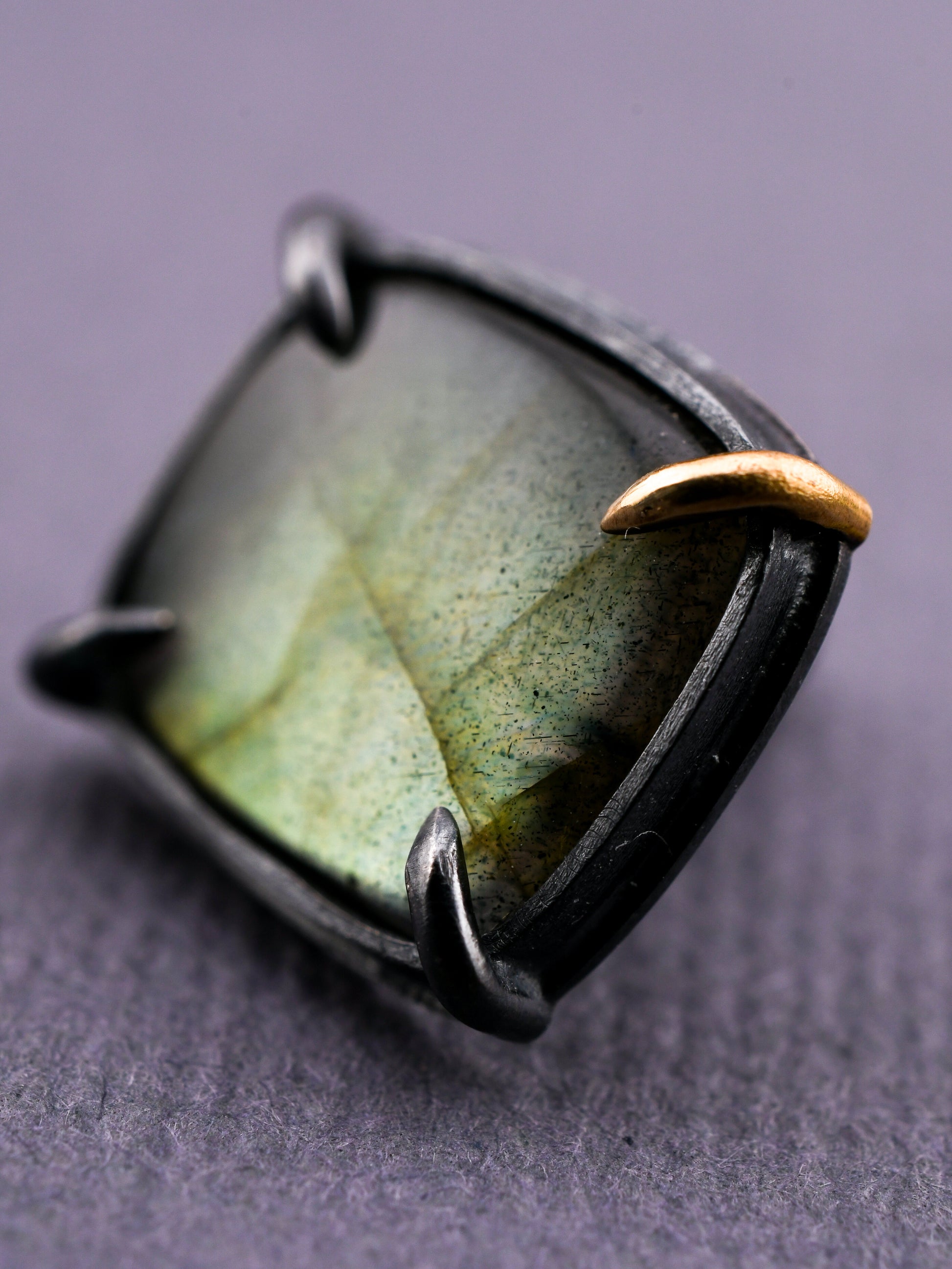 Ring with a green stone and gold accent on a gray background