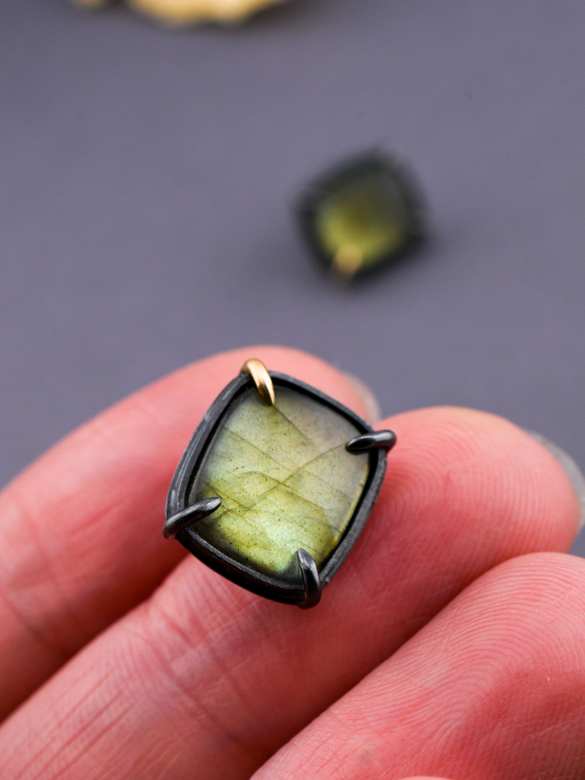 Green stone ring held between fingers against a dark background