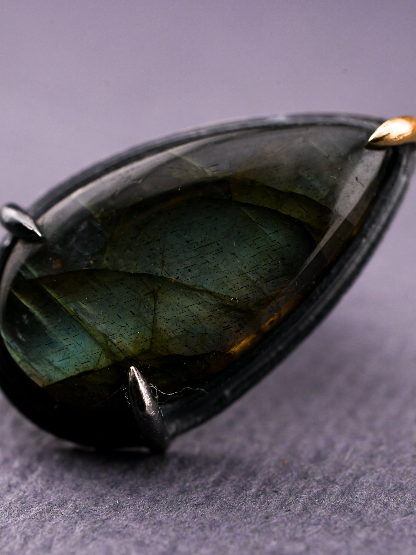 Teardrop-shaped gemstone earring on a gray background