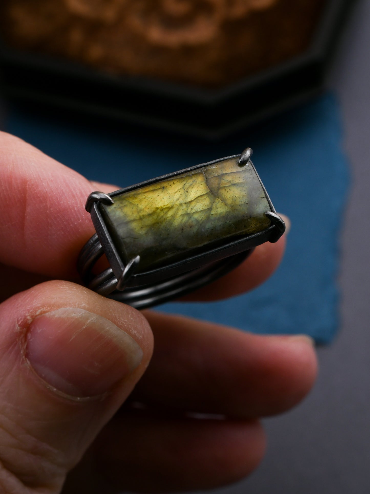Hand holding a rectangular stone ring with a blurred background