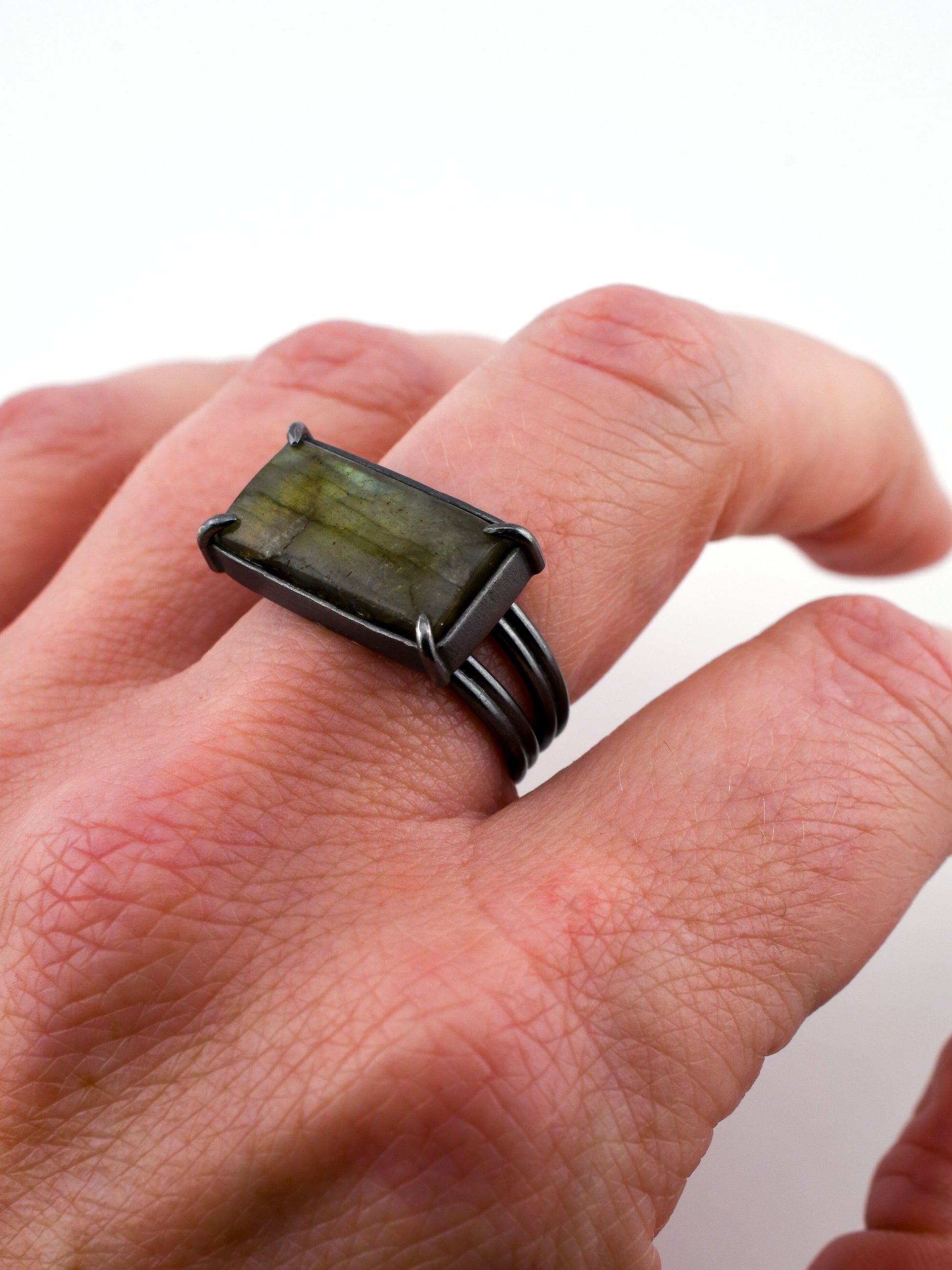 Hand wearing a ring with a green stone on a white background