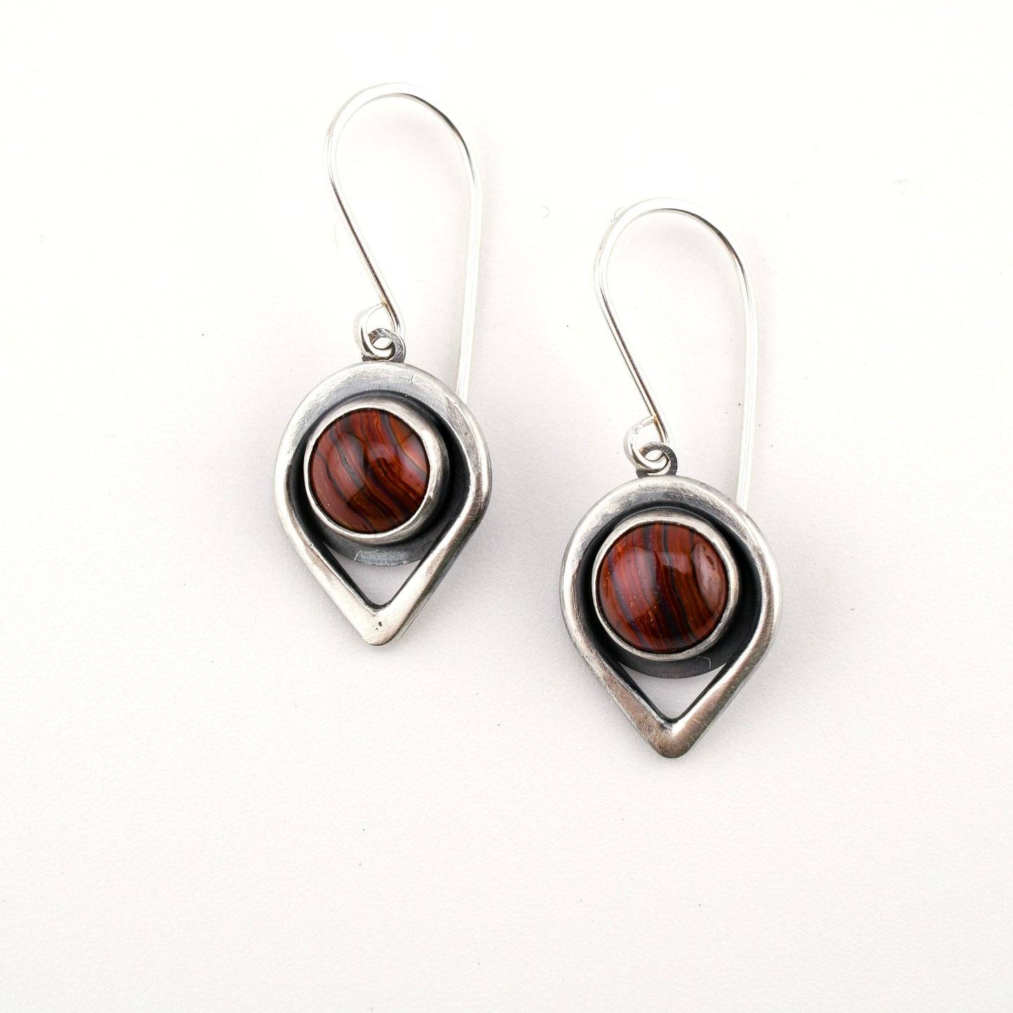 Pair of earrings with teardrop-shaped silver frames and brown gemstones on a white background