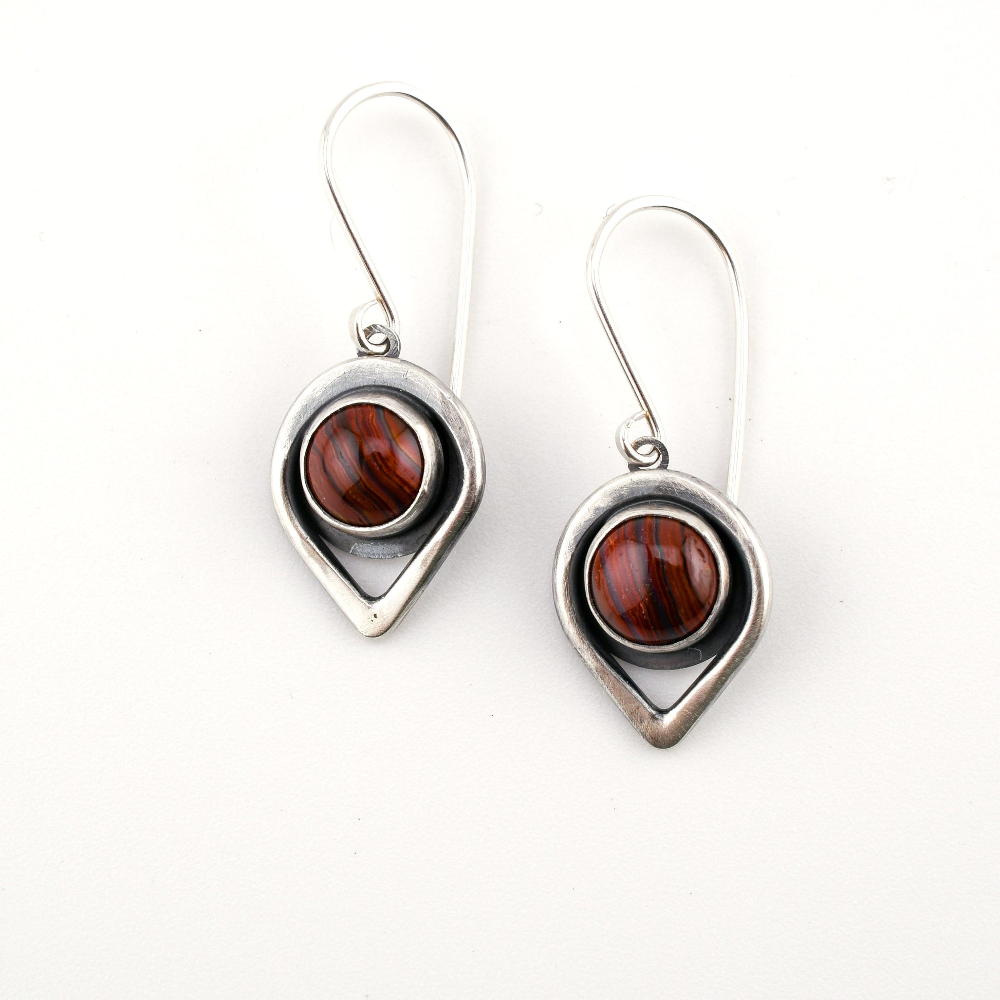 Pair of earrings with teardrop-shaped silver frames and brown gemstones on a white background