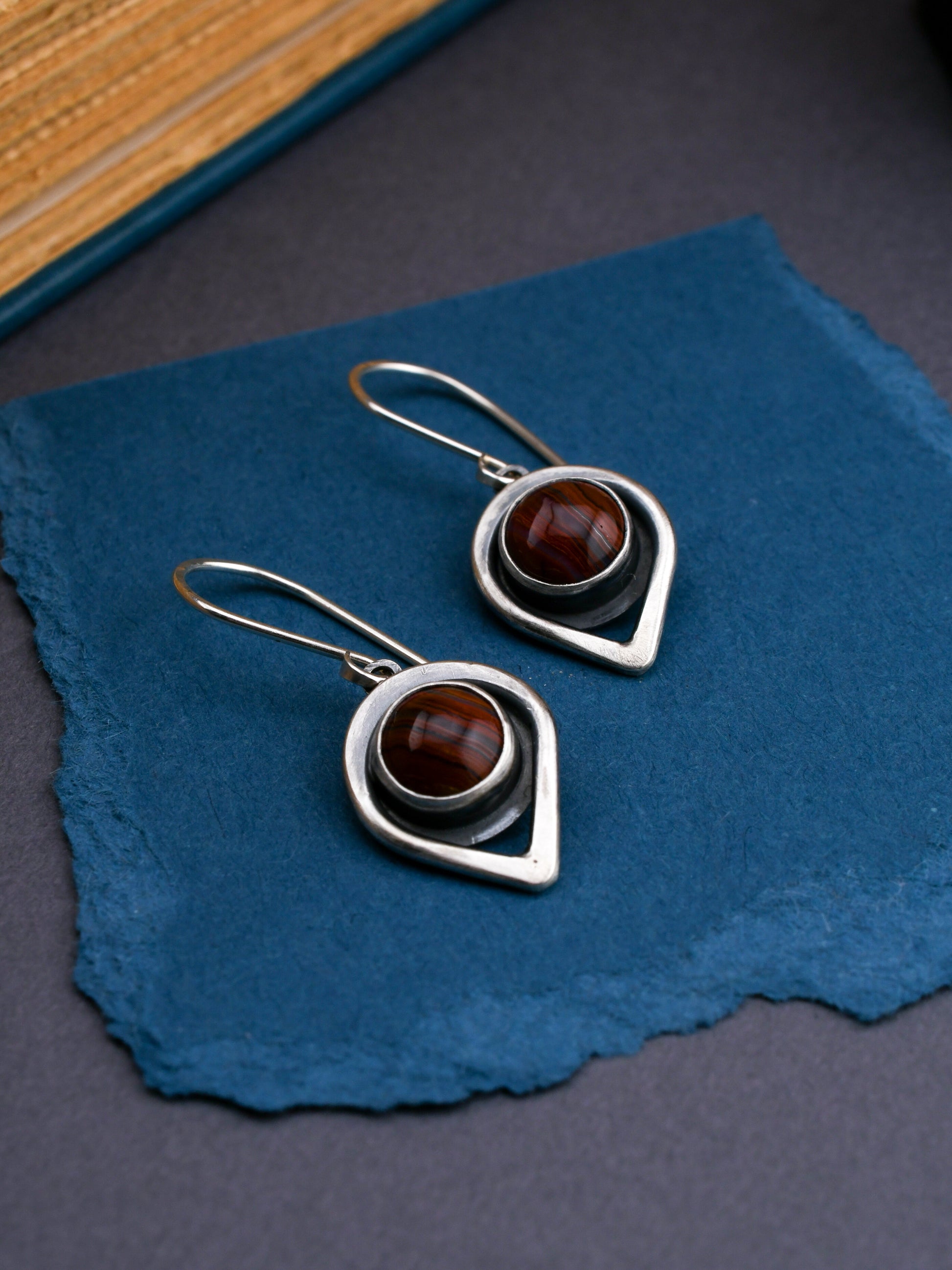 Silver earrings with red gemstones on a blue fabric background