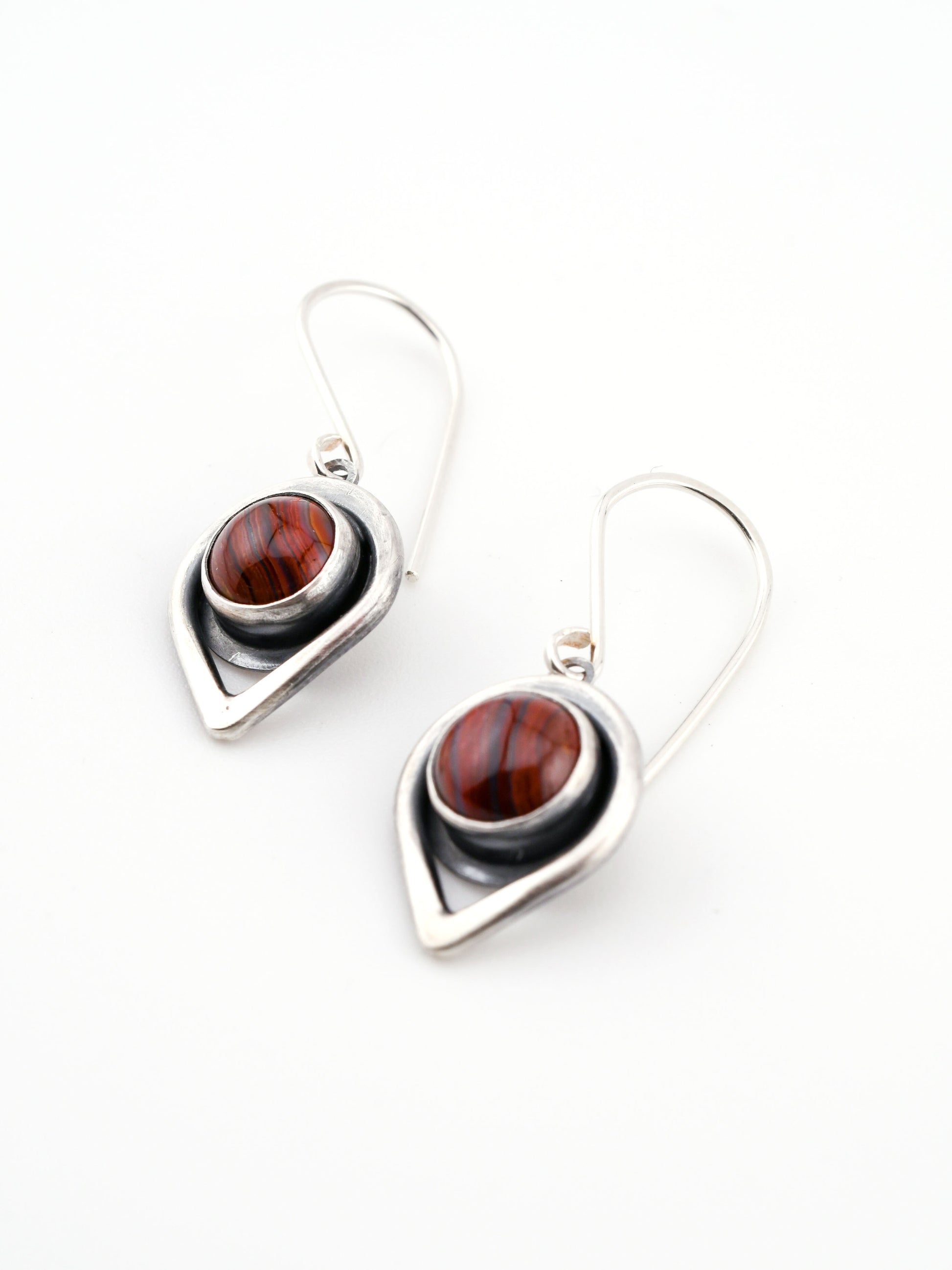 Pair of silver earrings with red stone centers on a white background