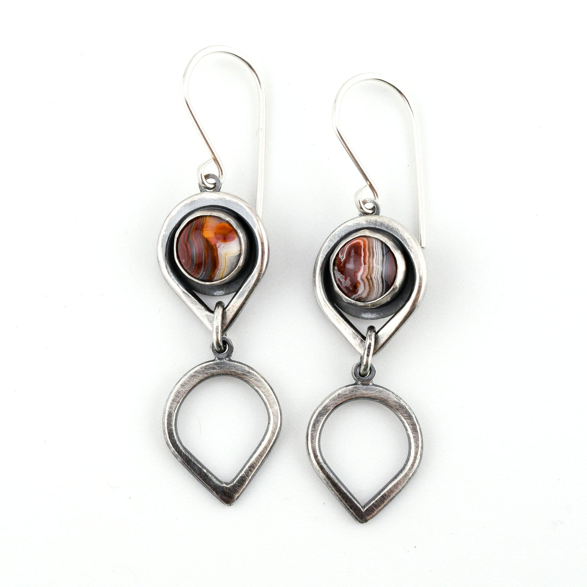 Pair of silver earrings with circular stones on a white background