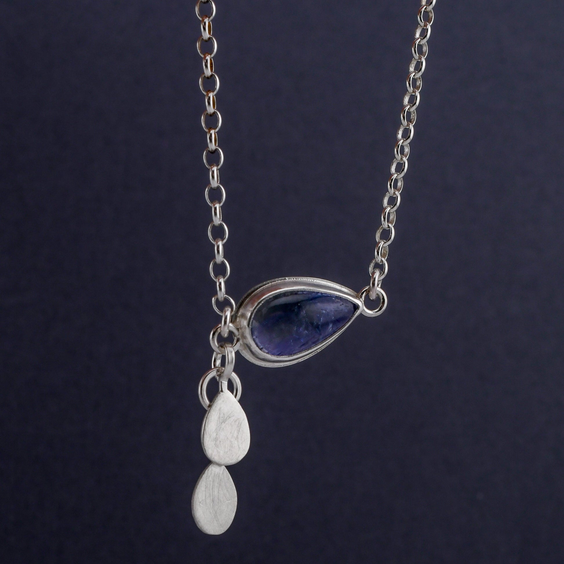 Silver necklace with a teardrop pendant on a dark background