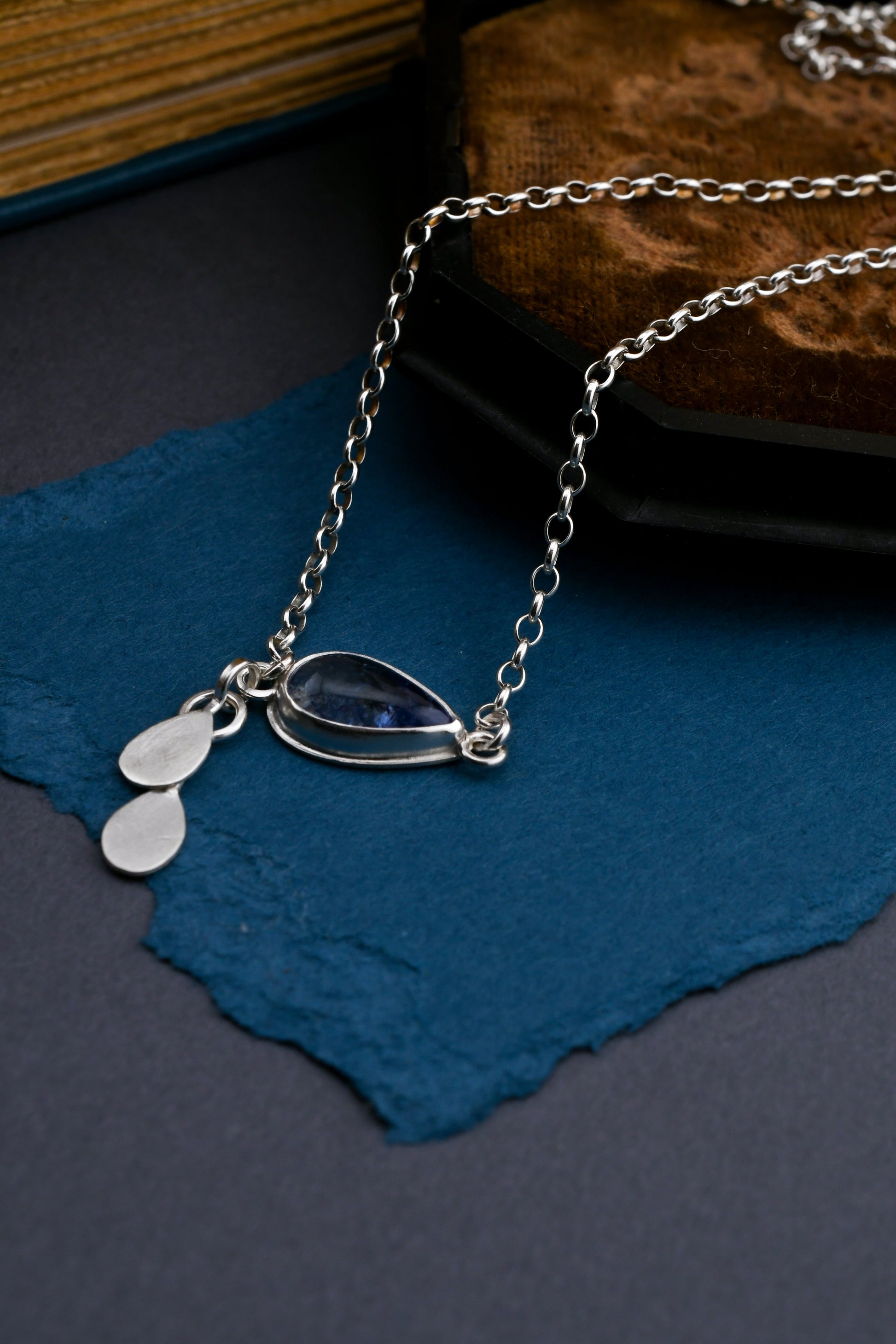 Silver necklace with pendant on a blue surface