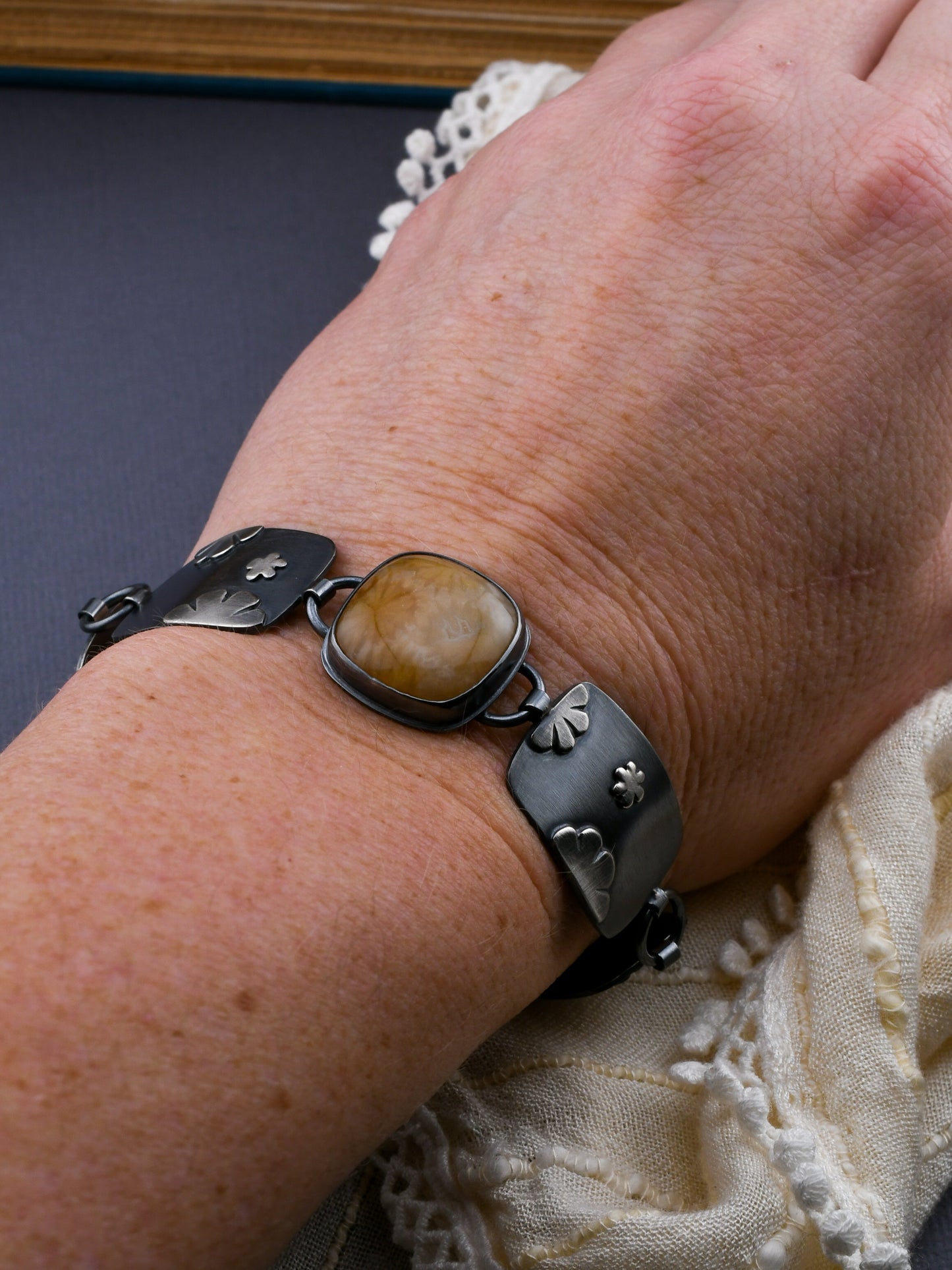 Link bracelet on a wrist with lace on a dark gray background