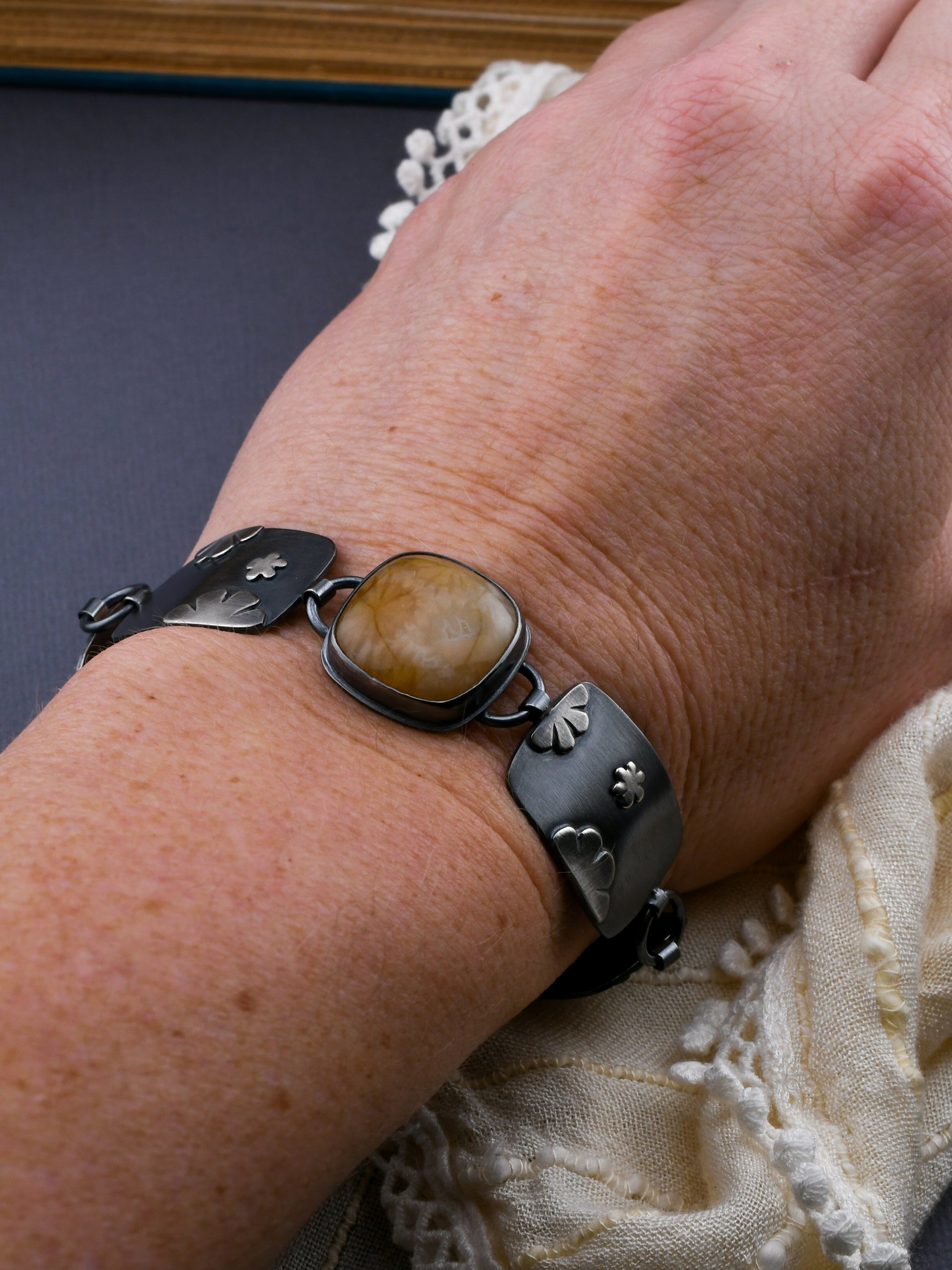 Link bracelet on a wrist with lace on a dark gray background