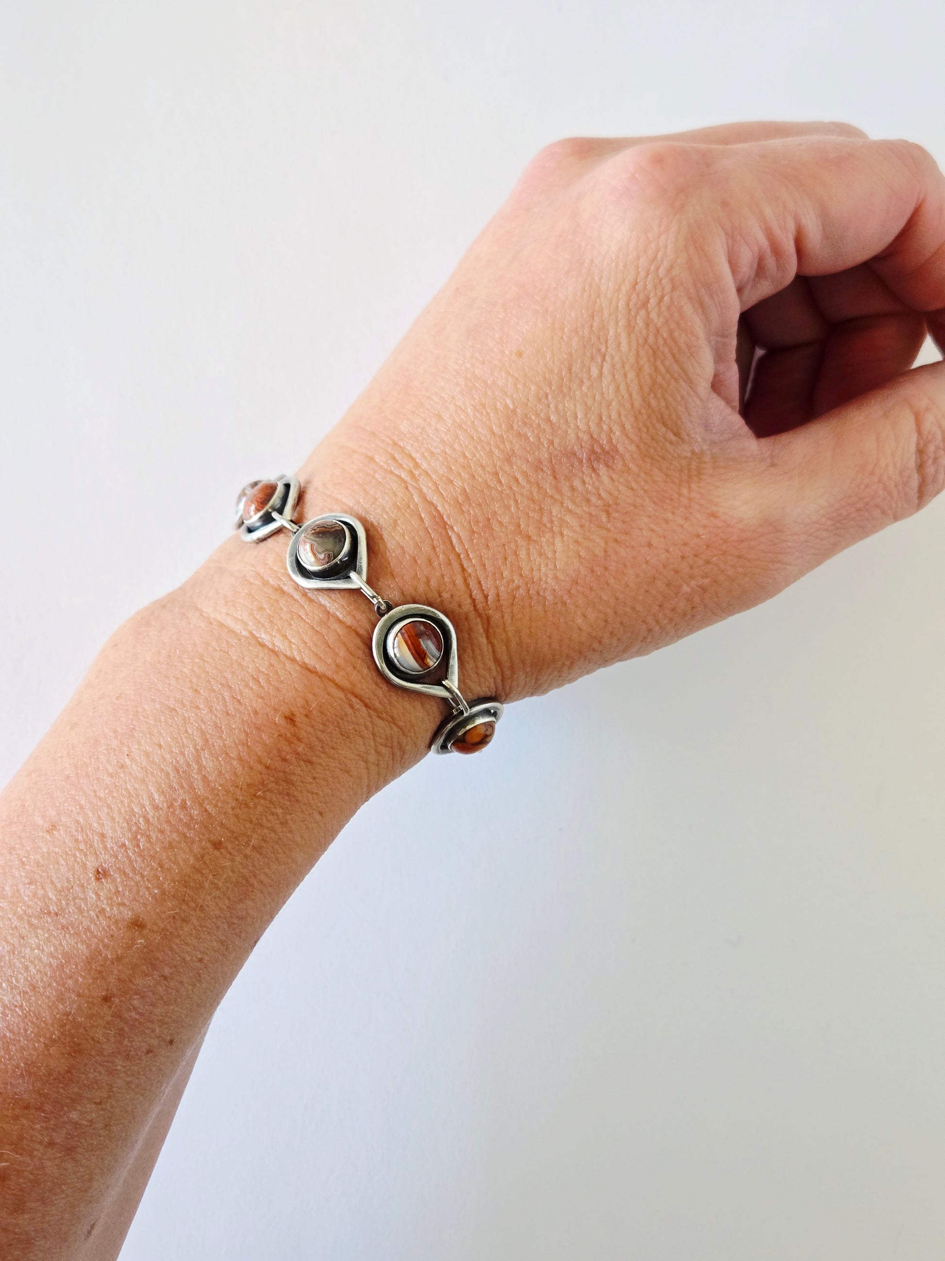 Wrist with teardrop linked silver bracelet with round agates 