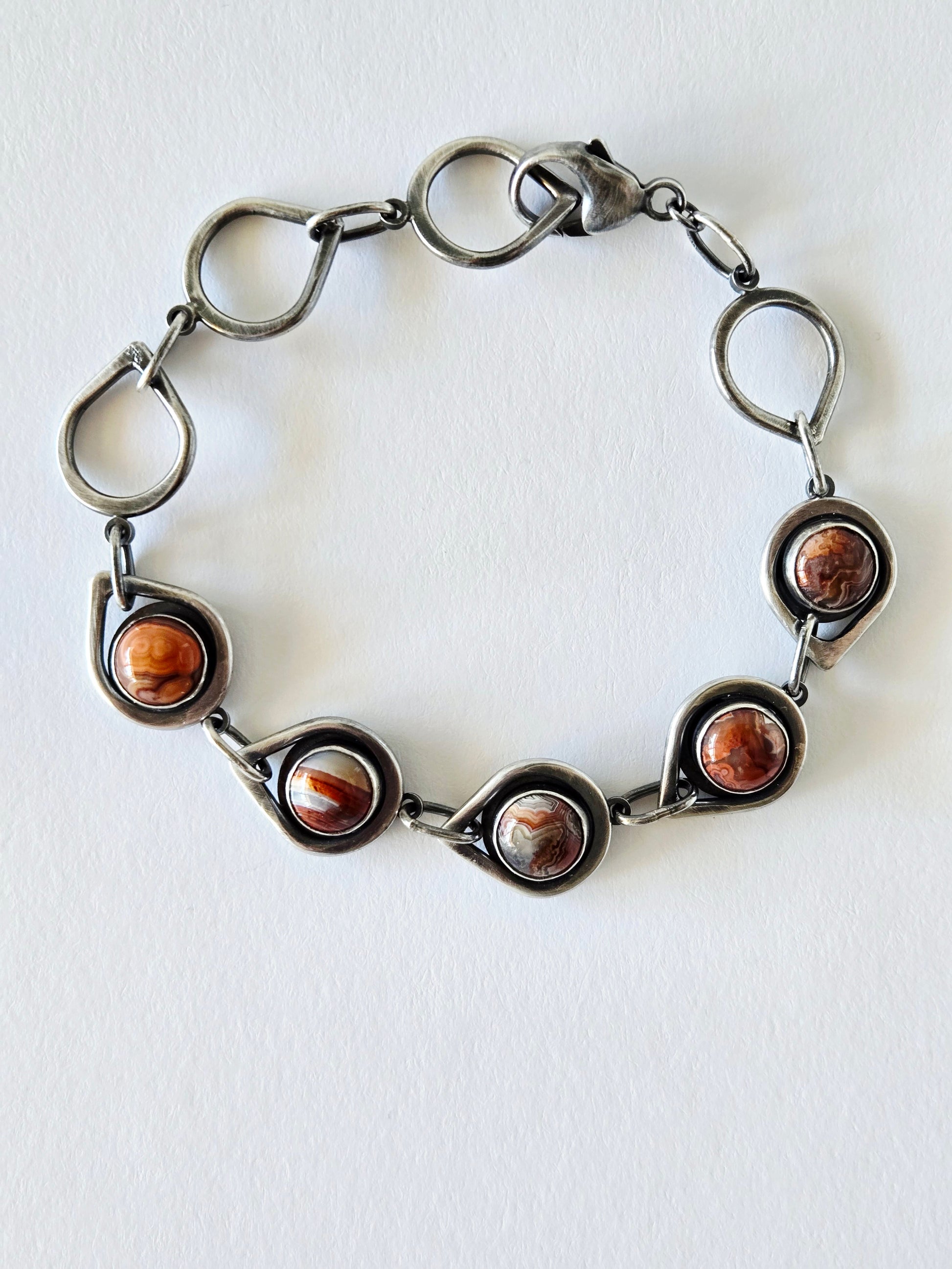 Silver bracelet with teardrop links and 5 circular agates on a white background