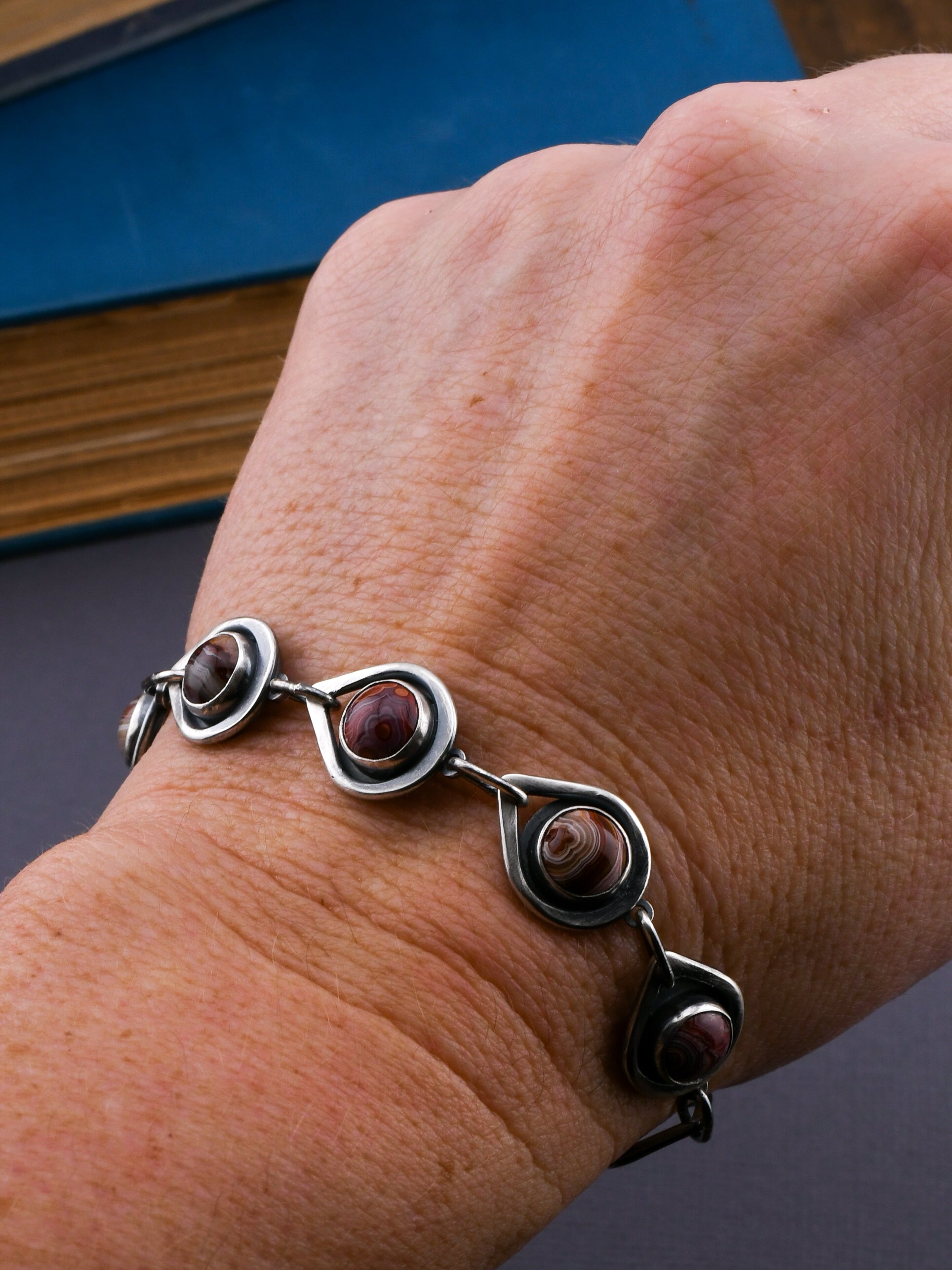 Silver bracelet with red stones on a wrist against a dark background
