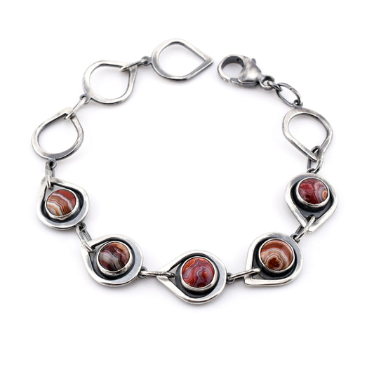 Silver bracelet with circular red stones on a white background