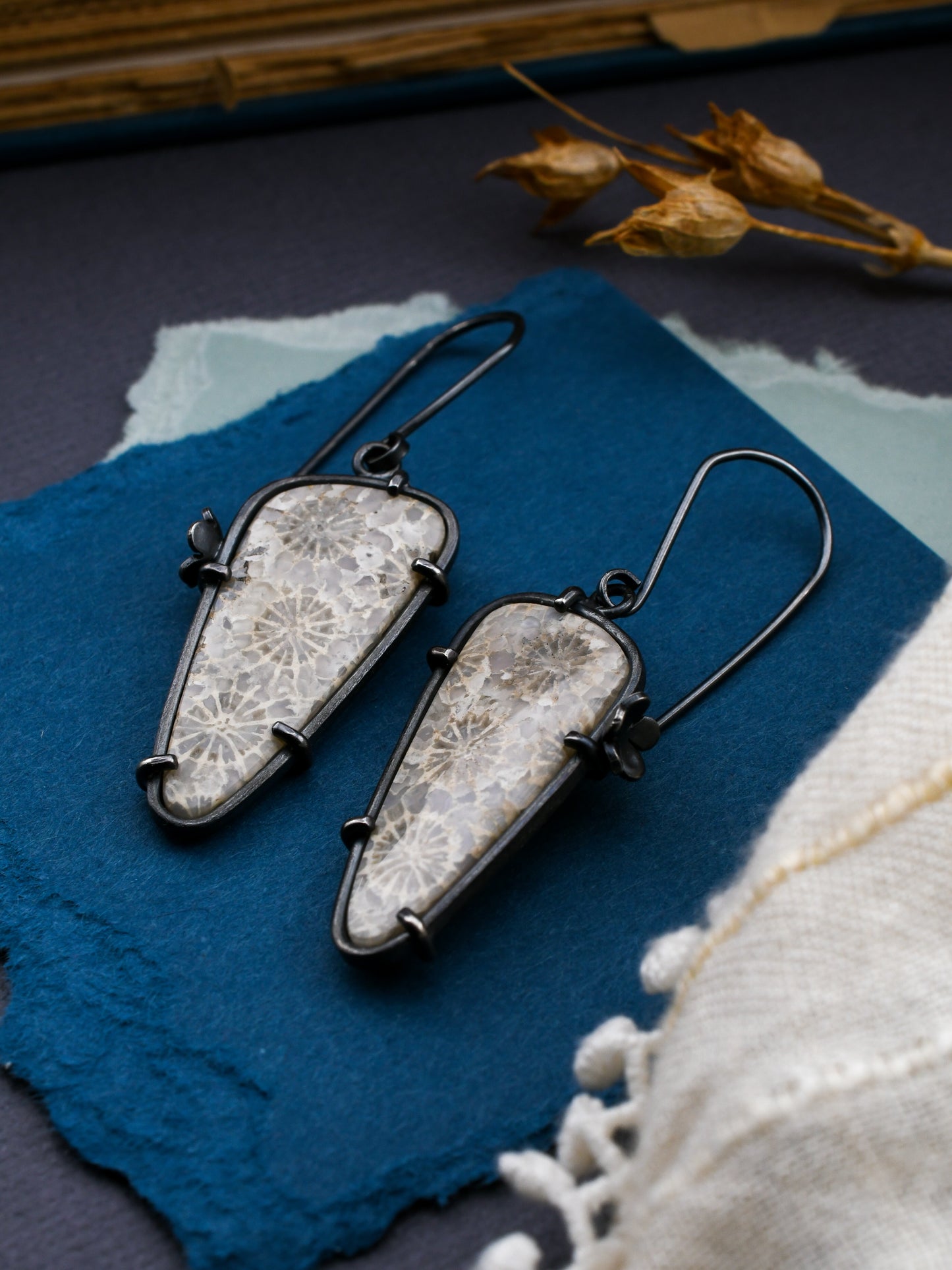 Pair of earrings with decorative stones on a textured blue surface