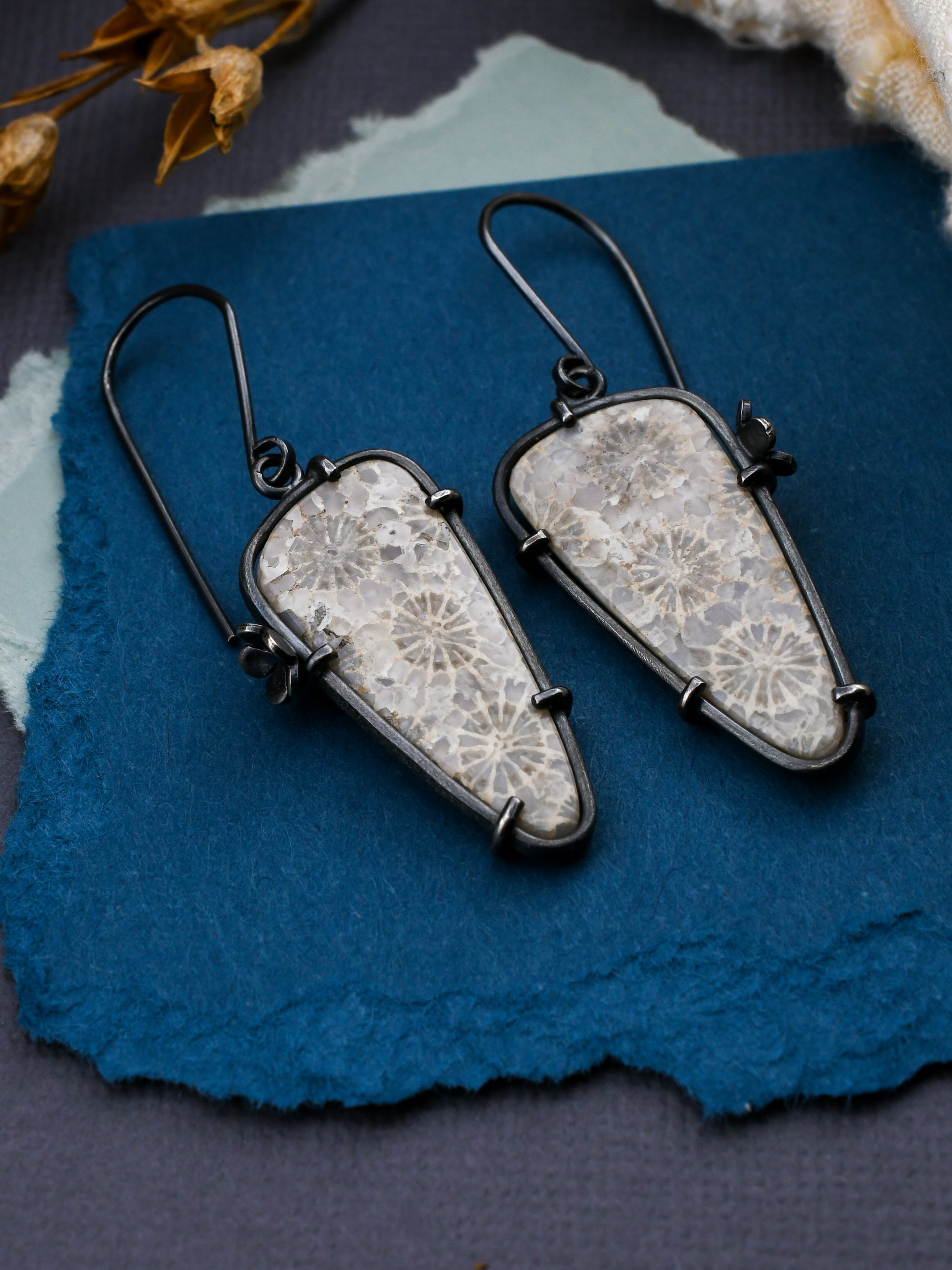 Pair of earrings with lace-like design on a blue textured surface
