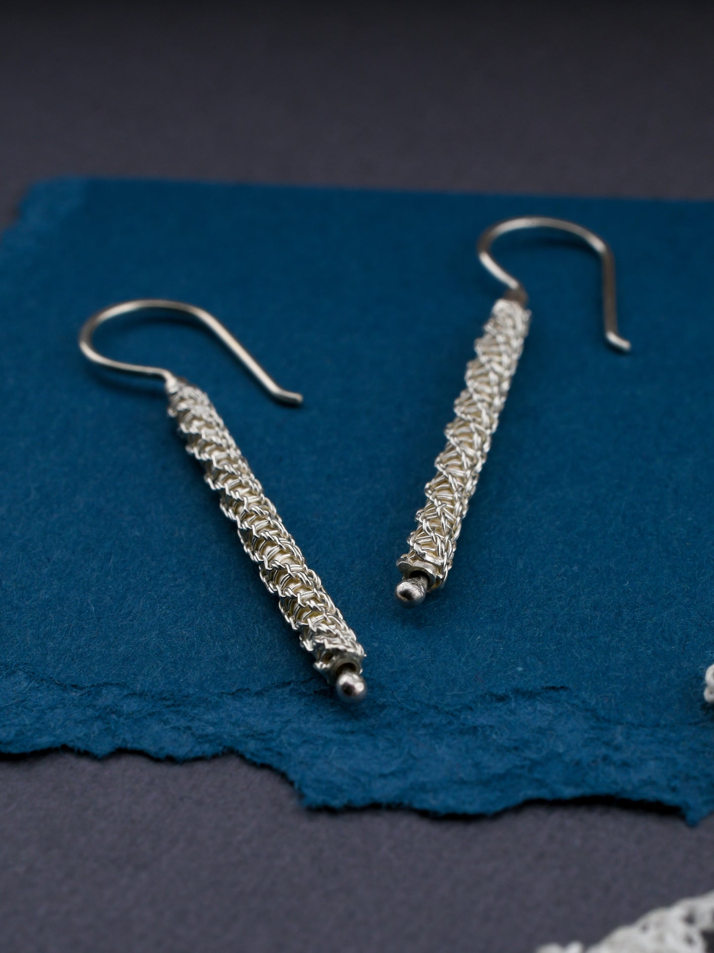 Silver earrings on a blue textured surface