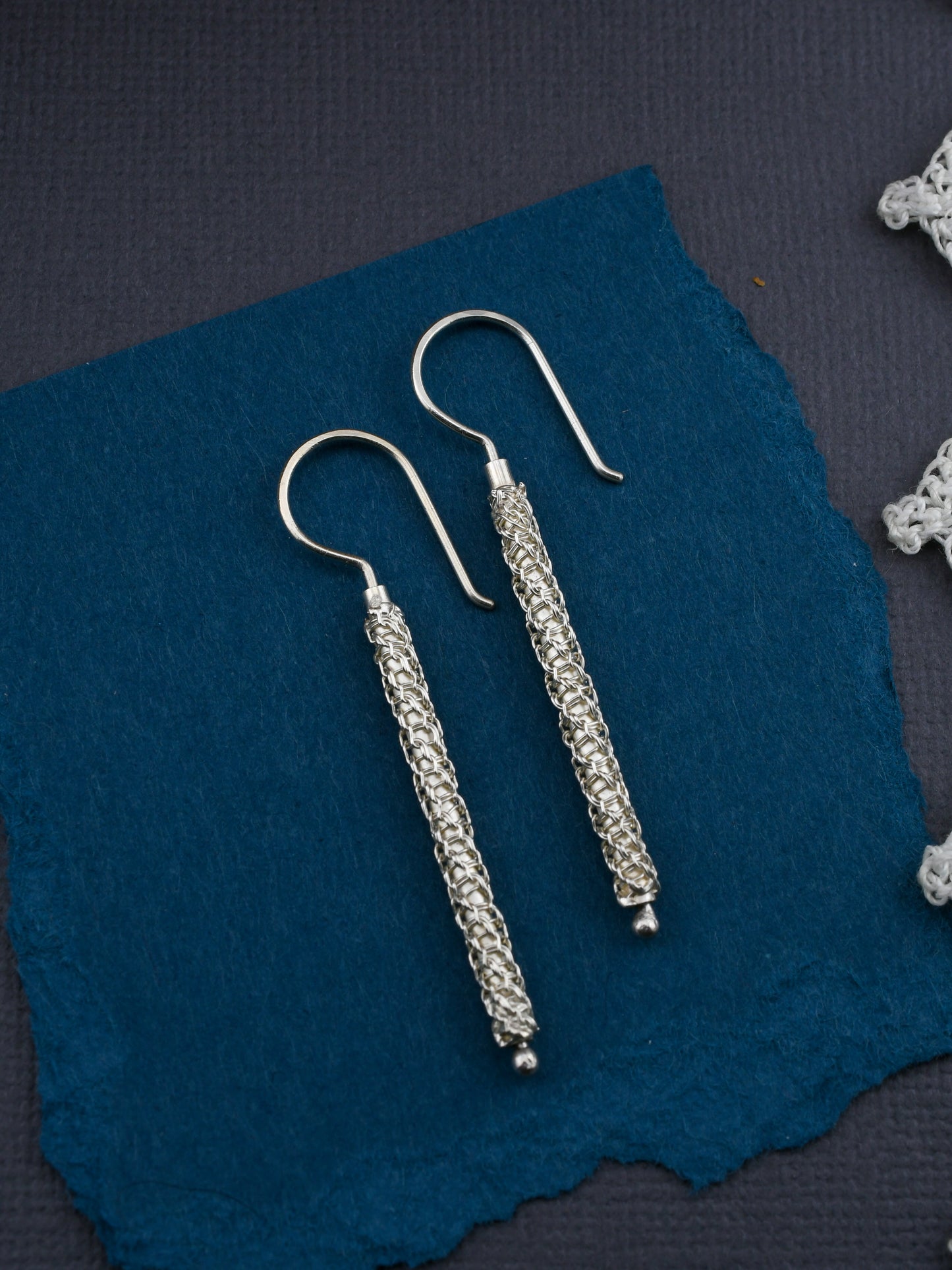 Pair of silver earrings on a blue fabric background