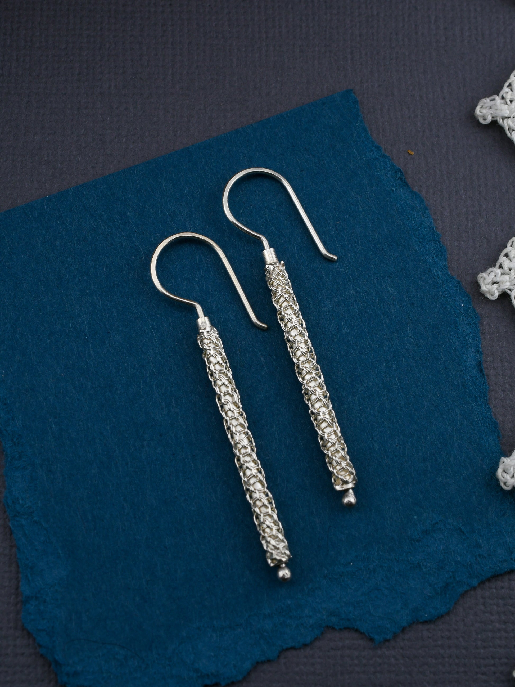 Pair of silver earrings on a blue fabric background