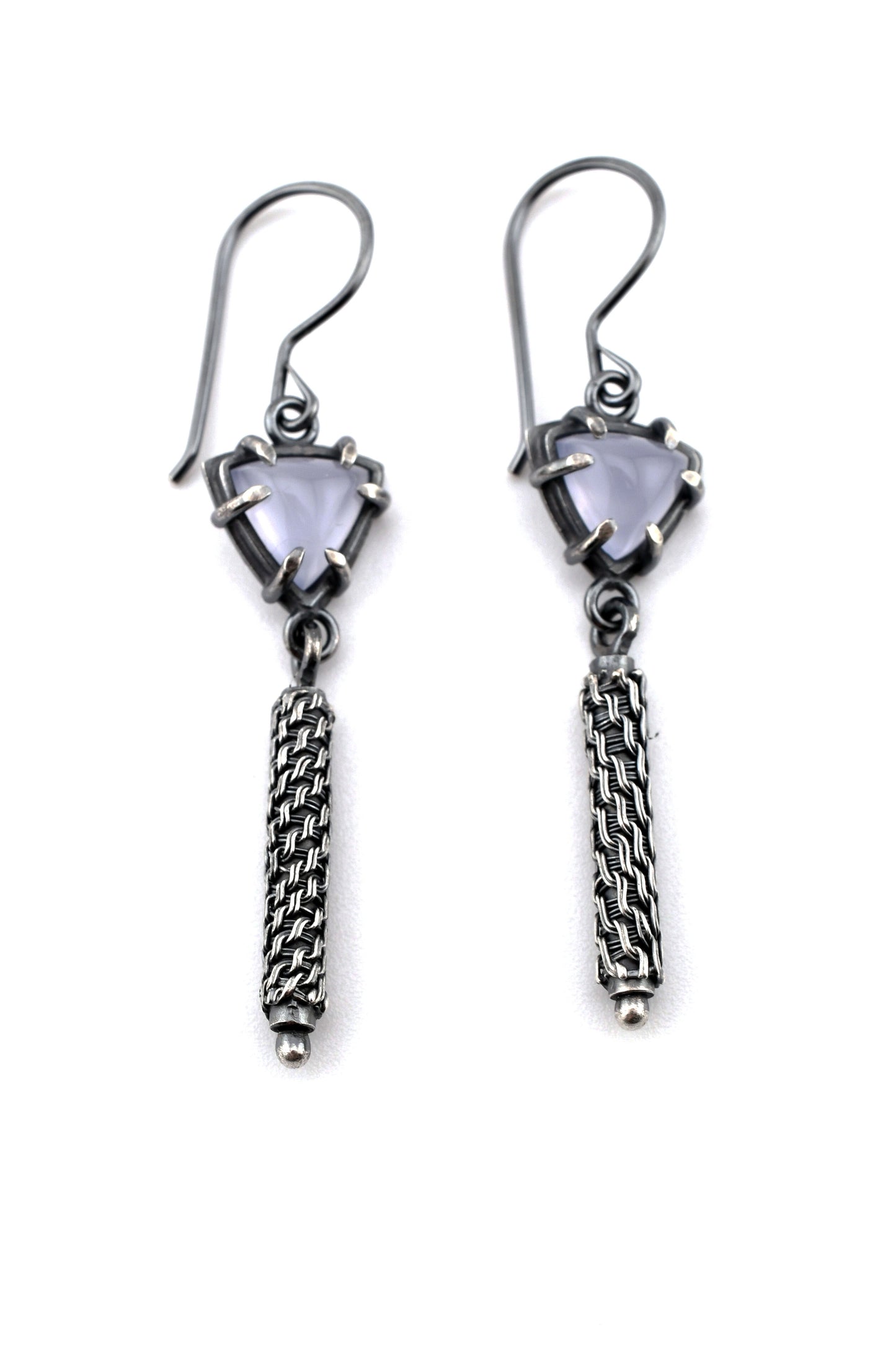 Pair of silver earrings with gemstones and woven details on a white background