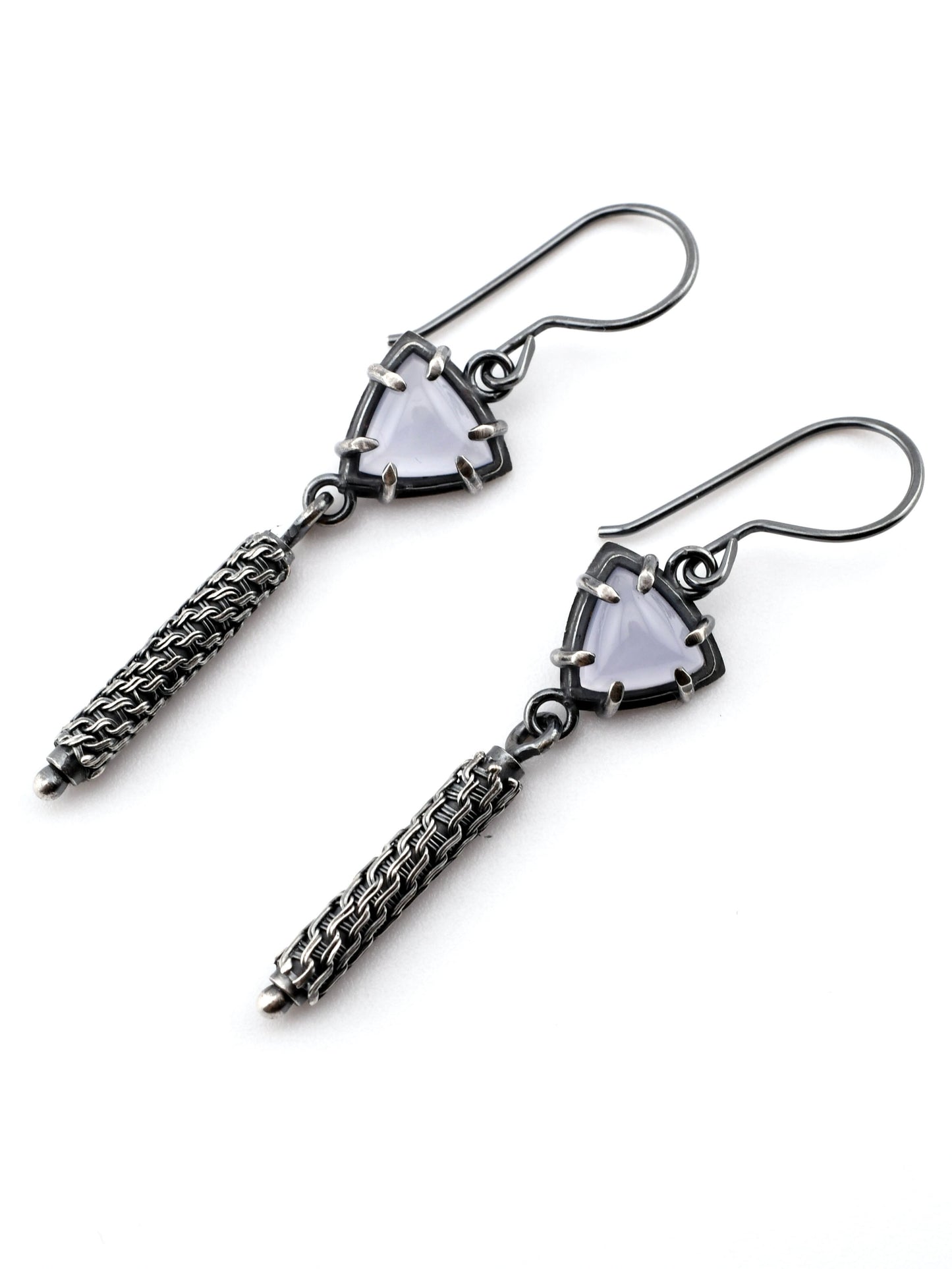 Pair of silver earrings with triangular gemstones on a white background