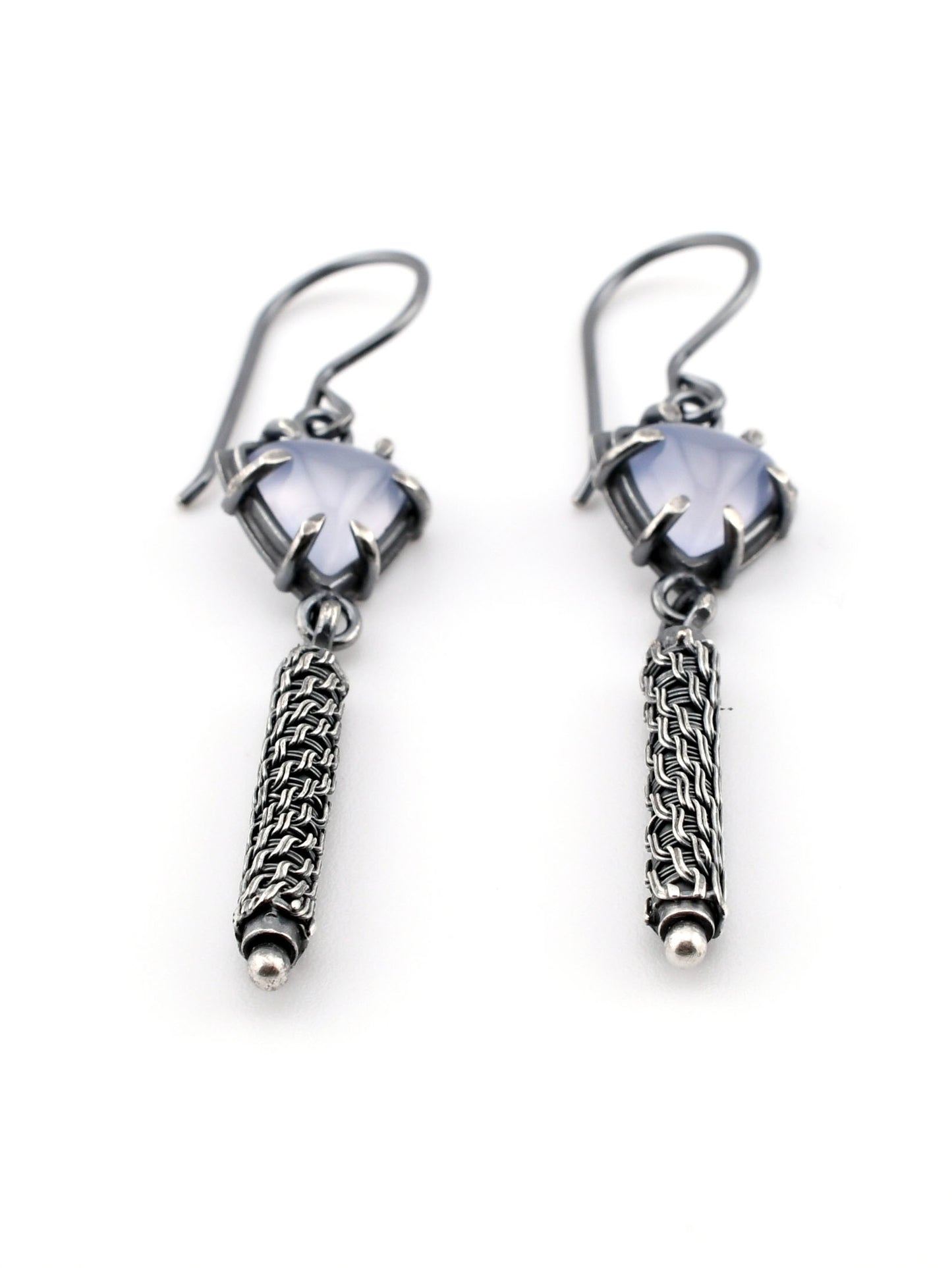 Pair of silver earrings with woven pendants on a white background