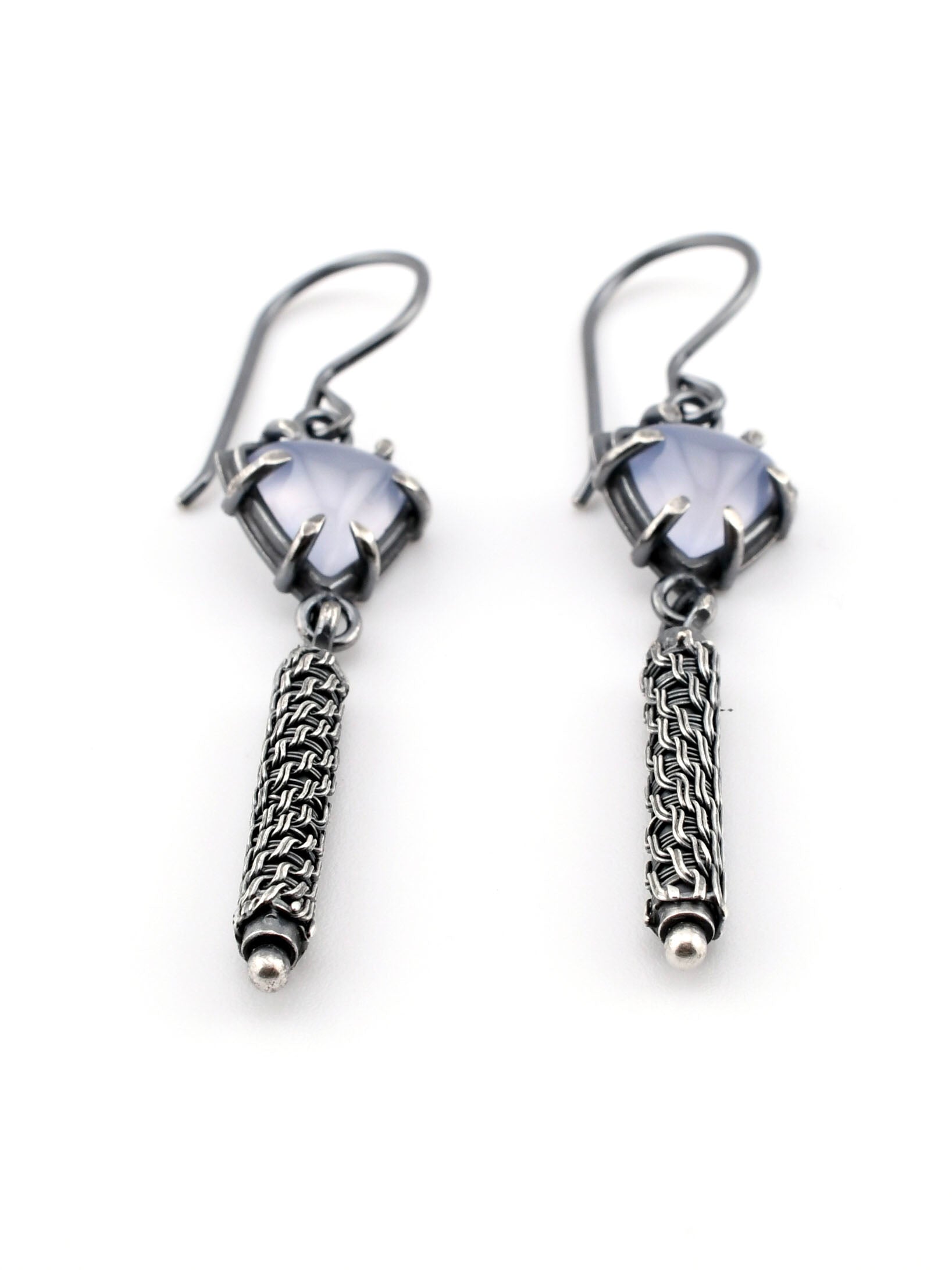 Pair of silver earrings with woven pendants on a white background