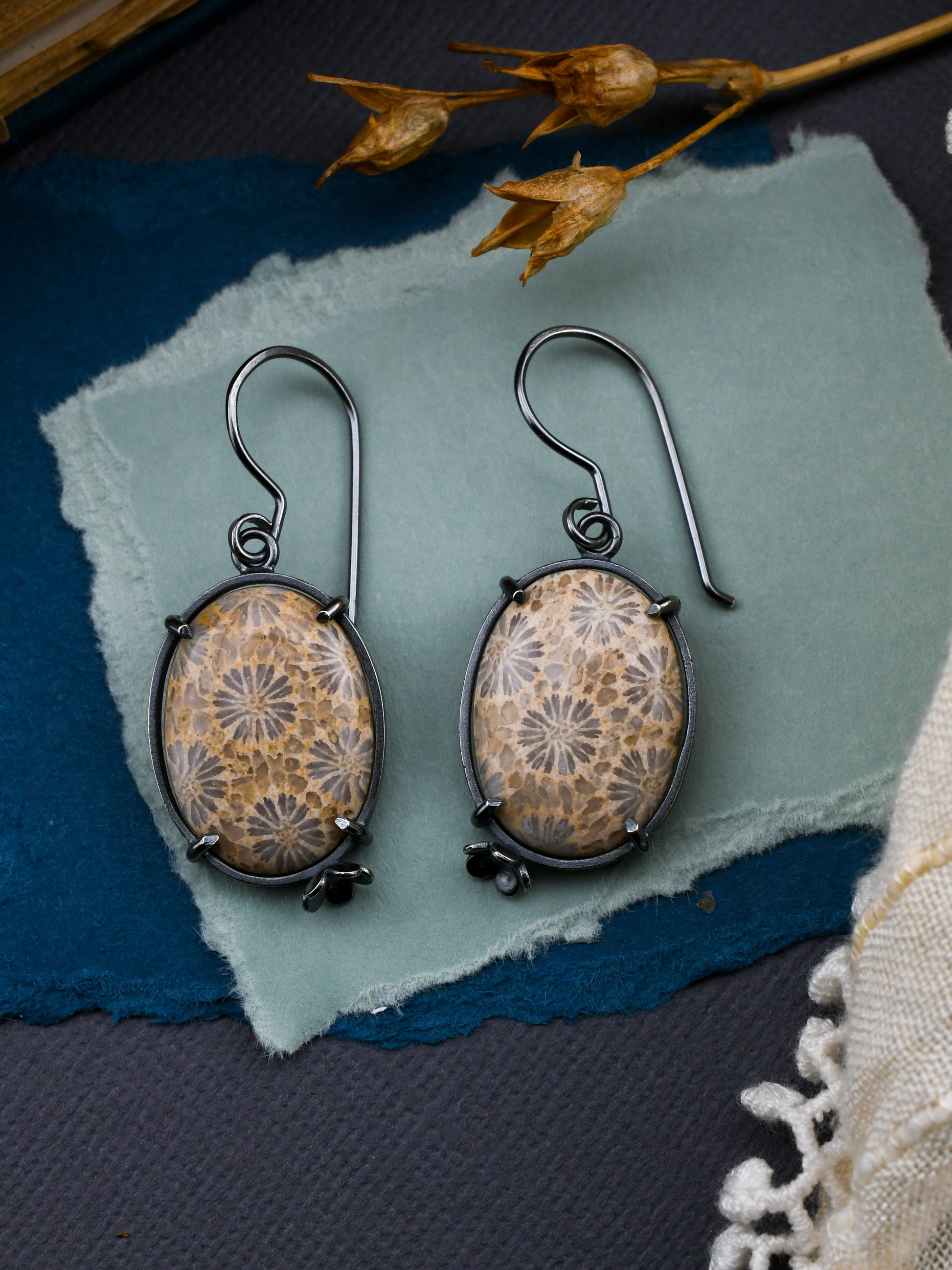 Pair of earrings with floral design on a textured surface