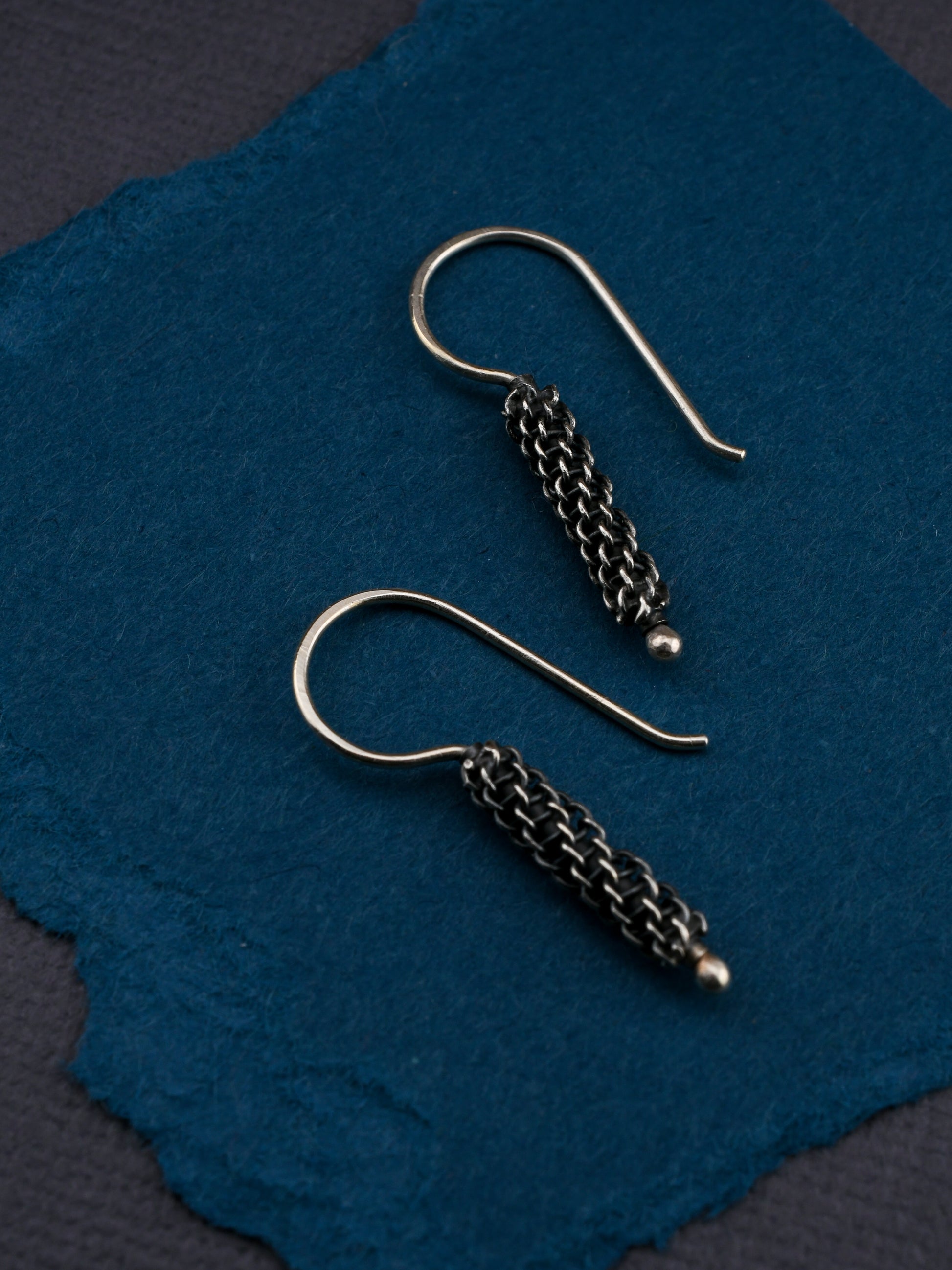 Pair of silver earrings on a textured blue surface