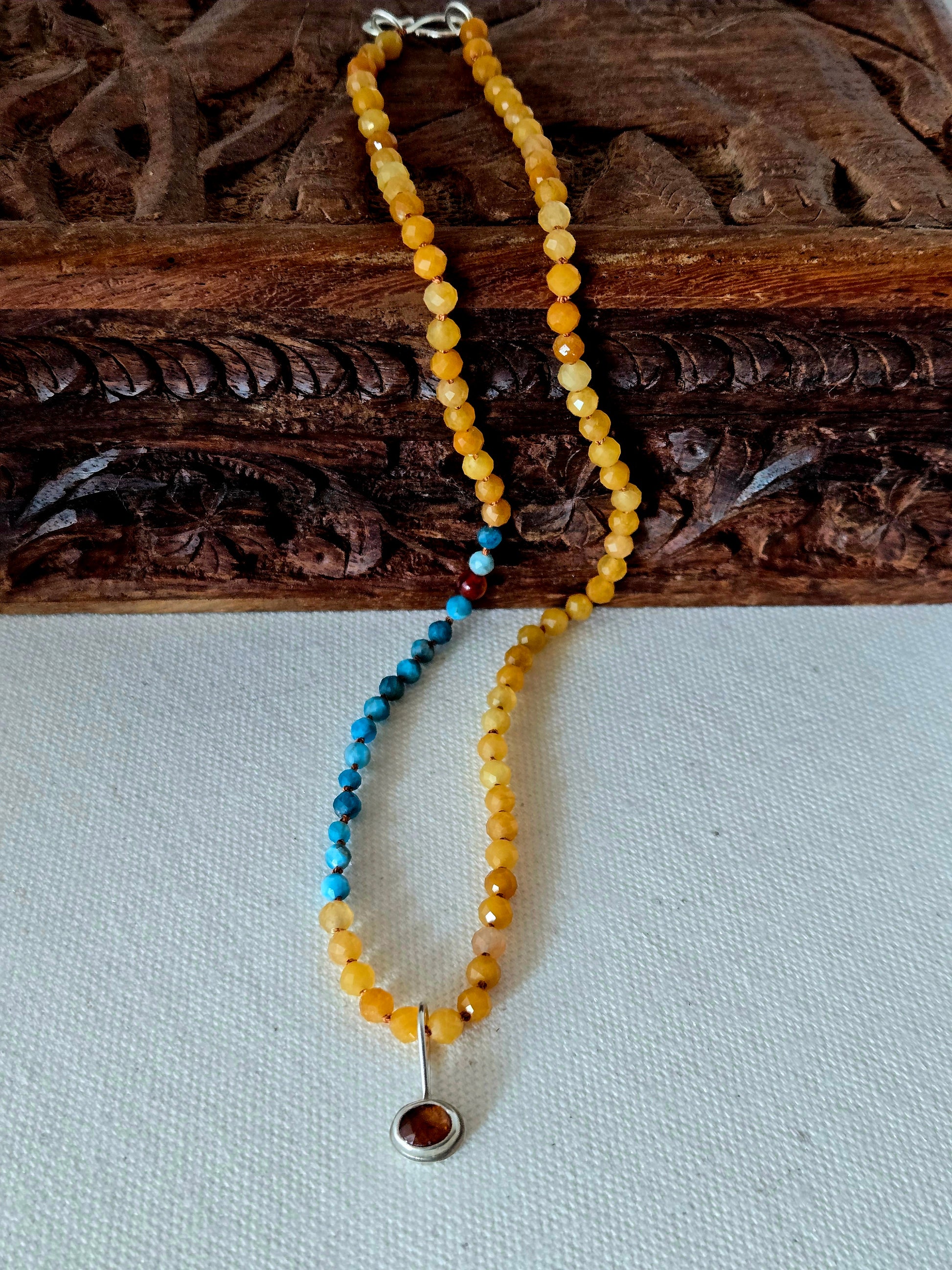 Beaded necklace with a pendant on a wooden surface