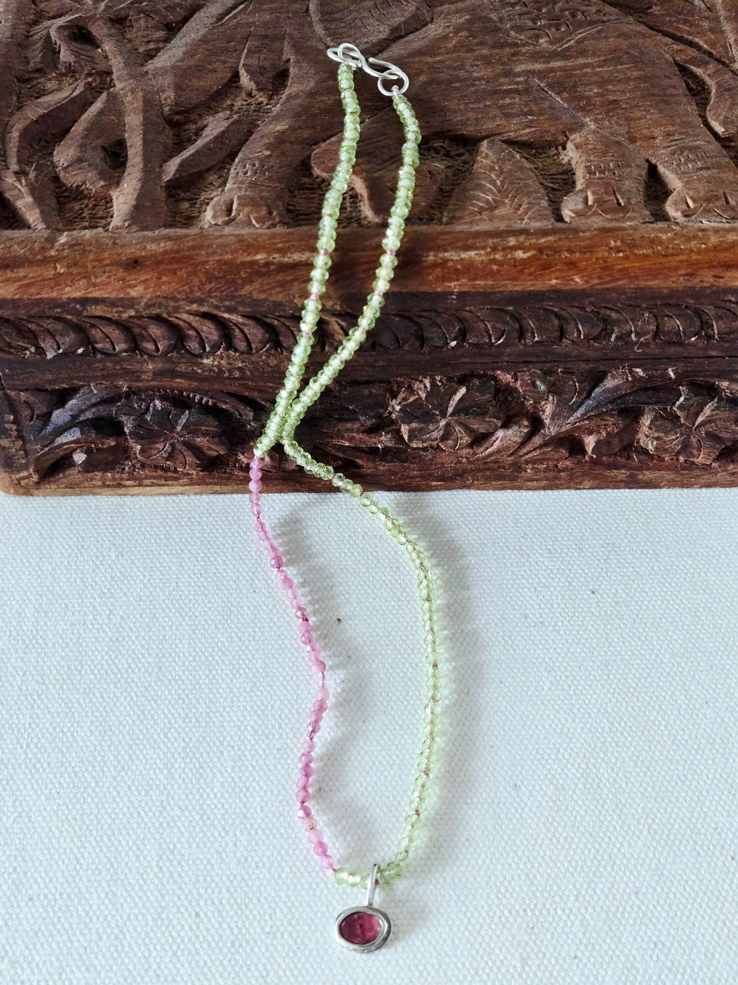 Necklace with pink and green beads on a wooden surface
