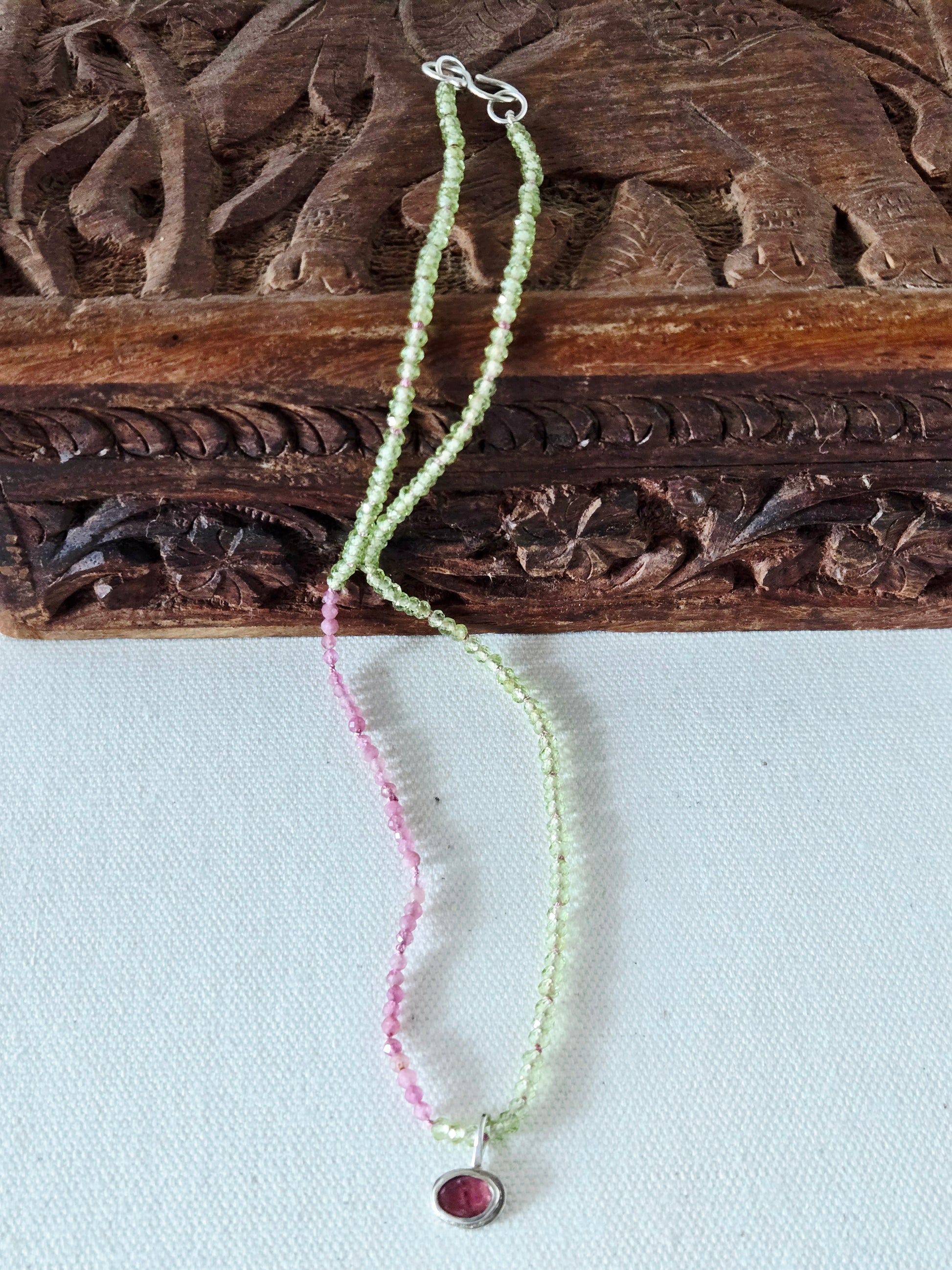 Necklace with pink and green beads on a wooden surface
